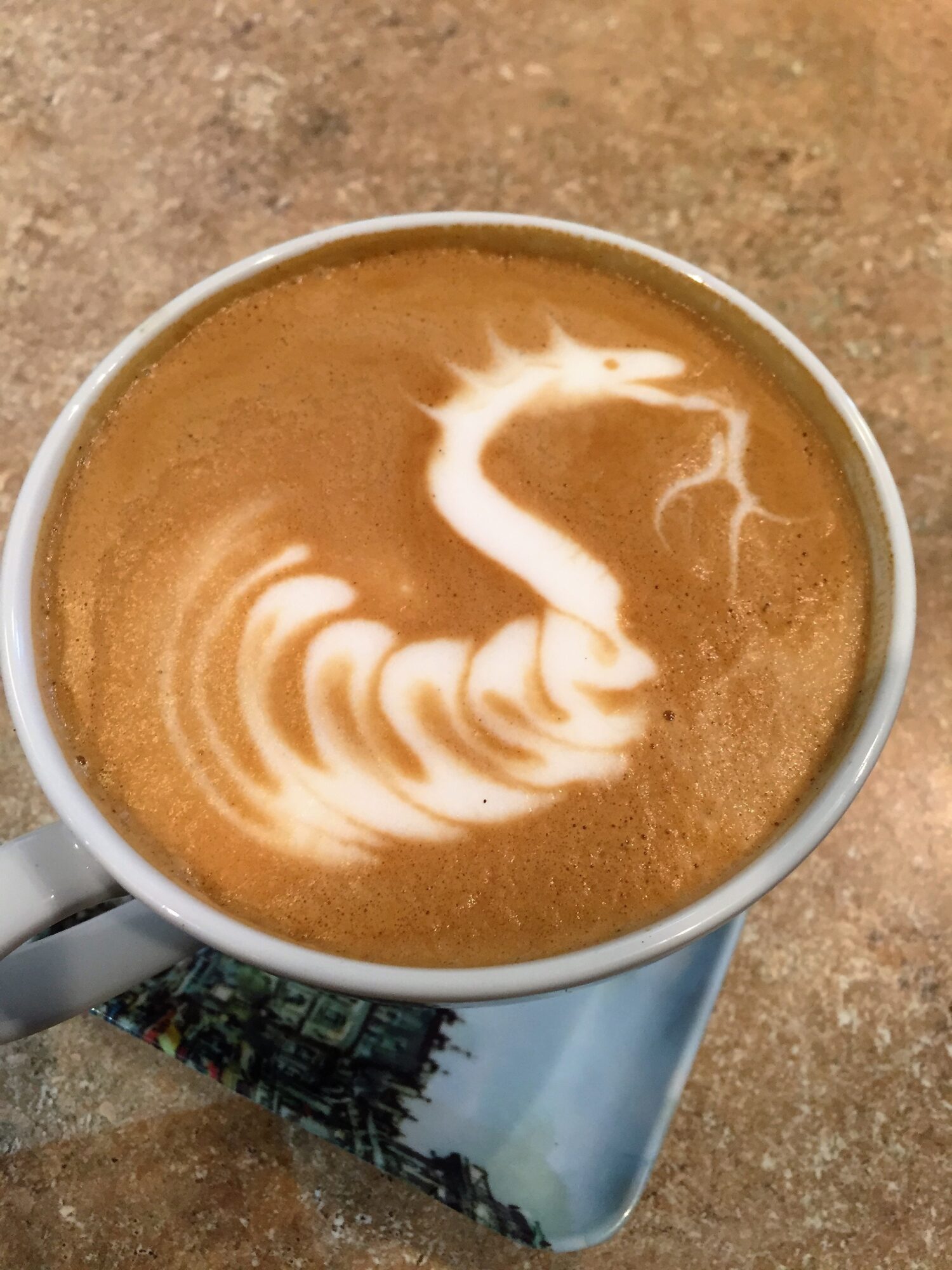 Coffee cup with latte art resembling a swan, on a textured surface.