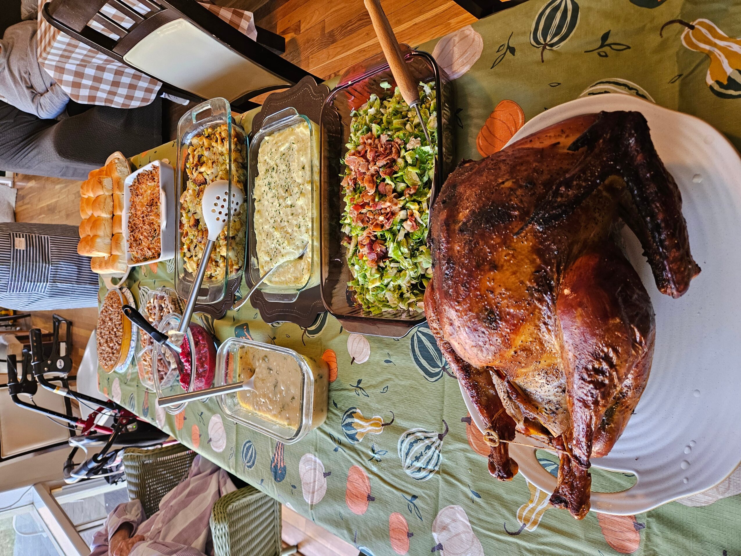 A large roasted turkey on a white plate, surrounded by various salads and side dishes on a table.