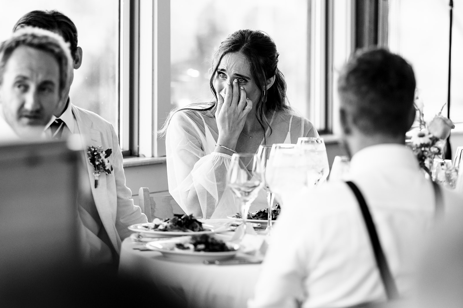 People sitting at a table during a meal, with a woman covering her face, in a black and white photo.