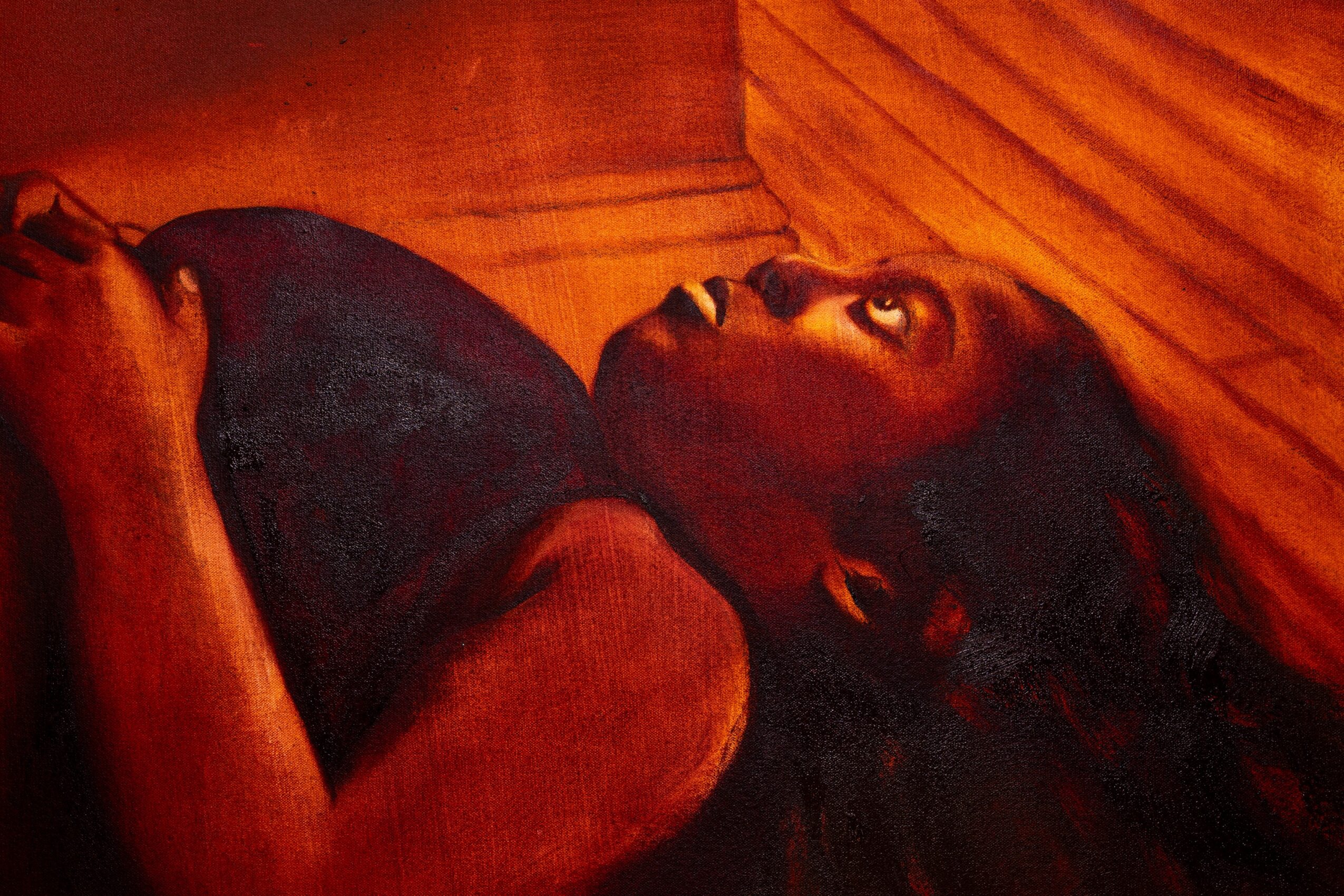 Person lying on a wooden surface, looking upward with a surprised expression, warm lighting, dark hair, and dark clothing.