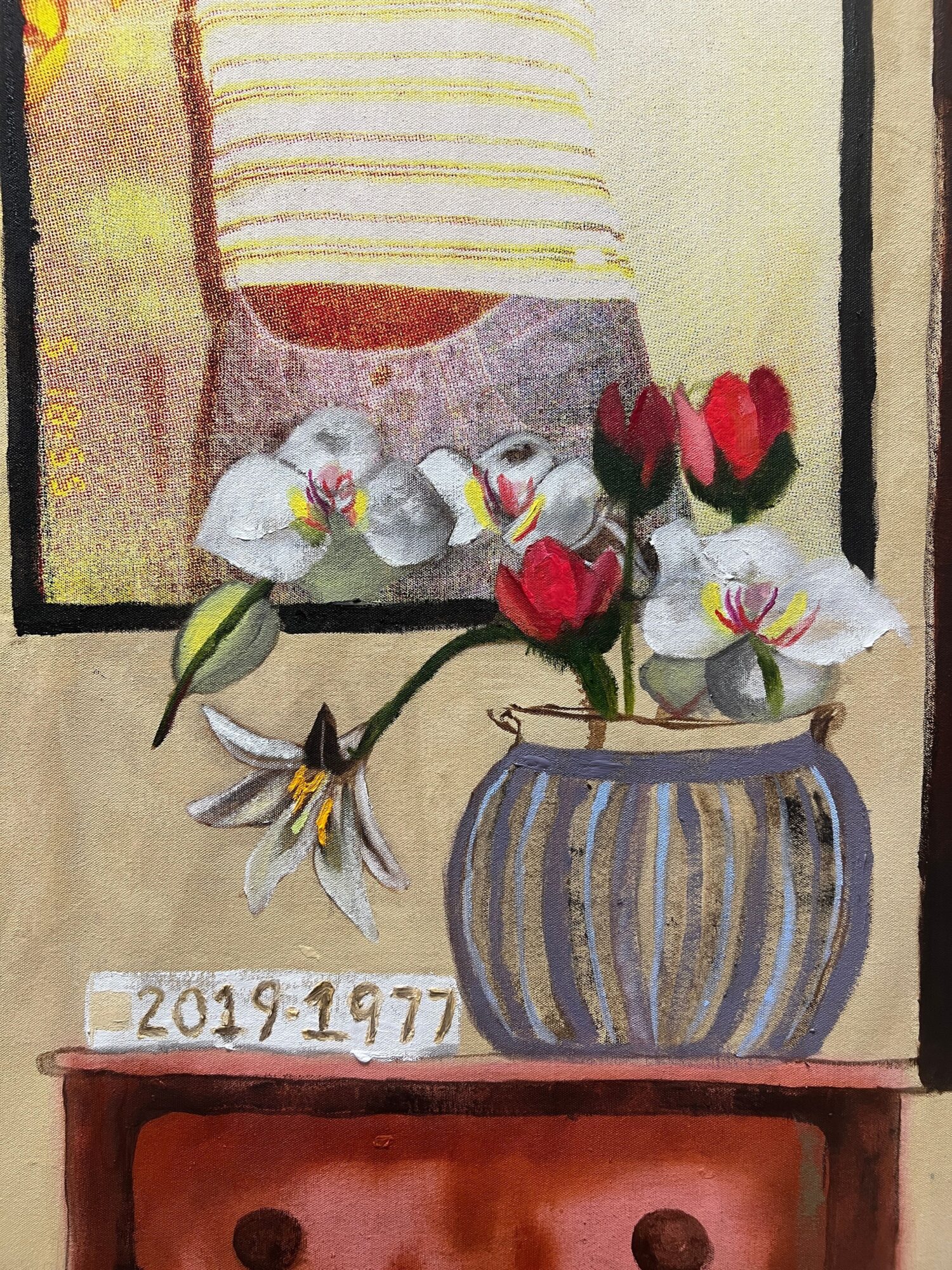 Flowers in a vase, a striped container, and a wooden drawer with a date, arranged on a surface.