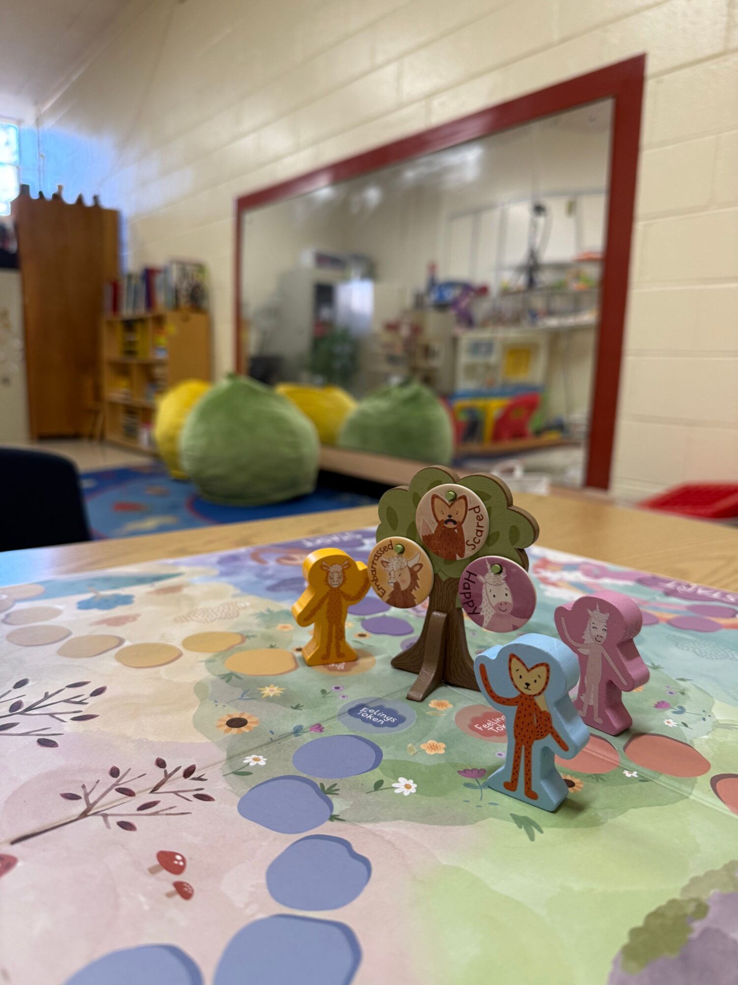 Colorful paper animal figures on a table with a blurred background of a room, books, and toys.