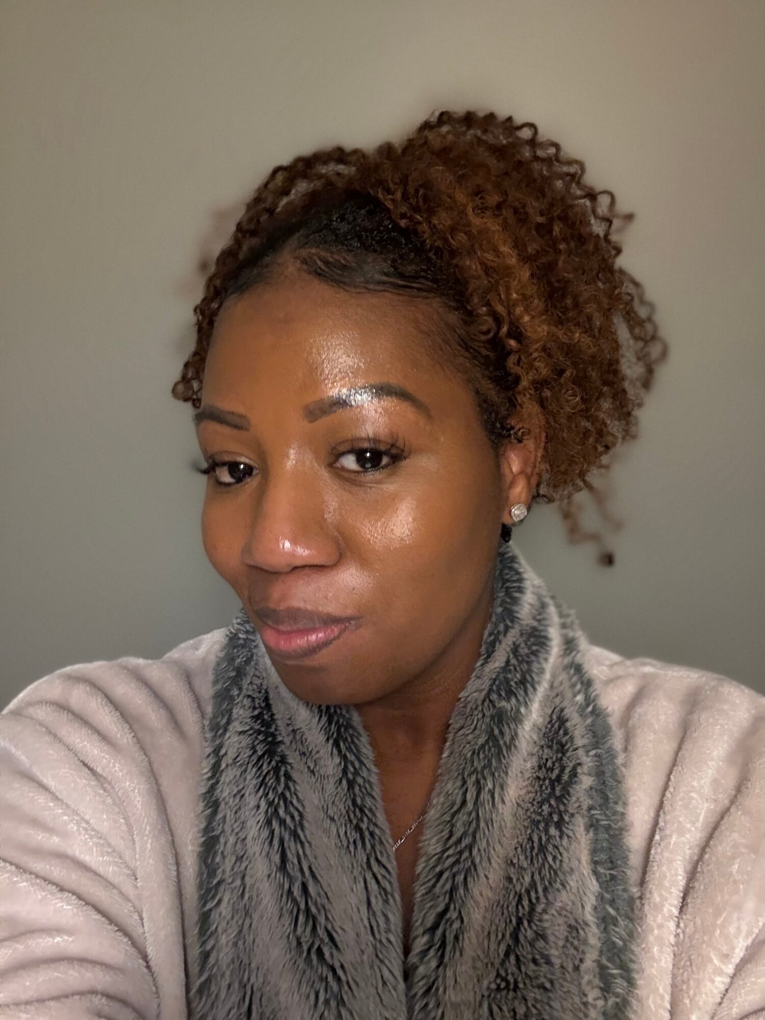 Portrait of a woman with curly hair, wearing a scarf and a light-colored sweater, looking at the camera.