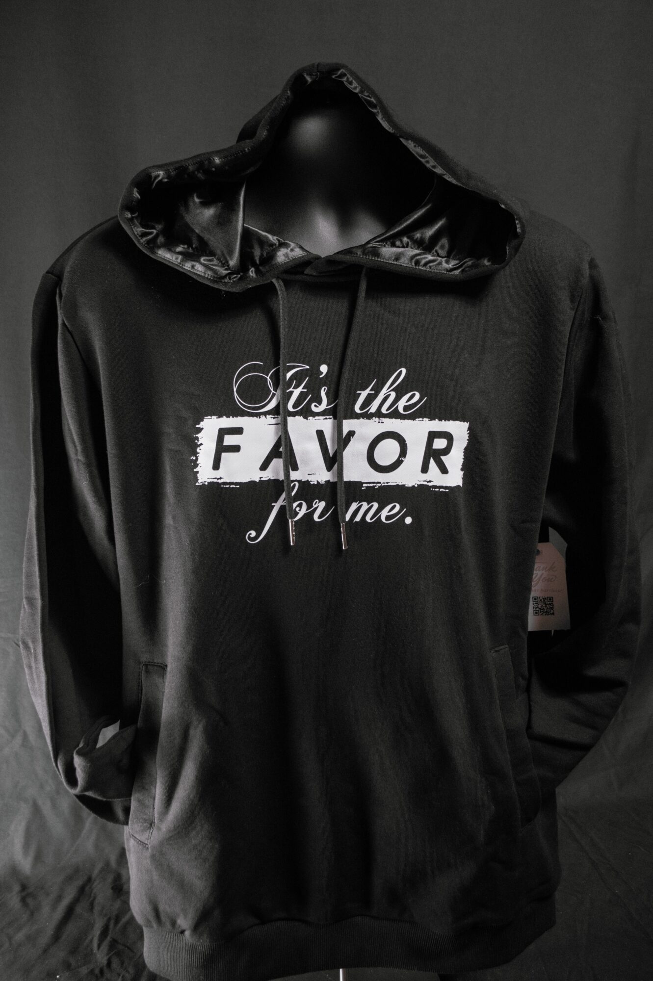 Black hoodie with a shiny hood and drawstrings, text reads 'It's the FAVOR for me.' on the front.