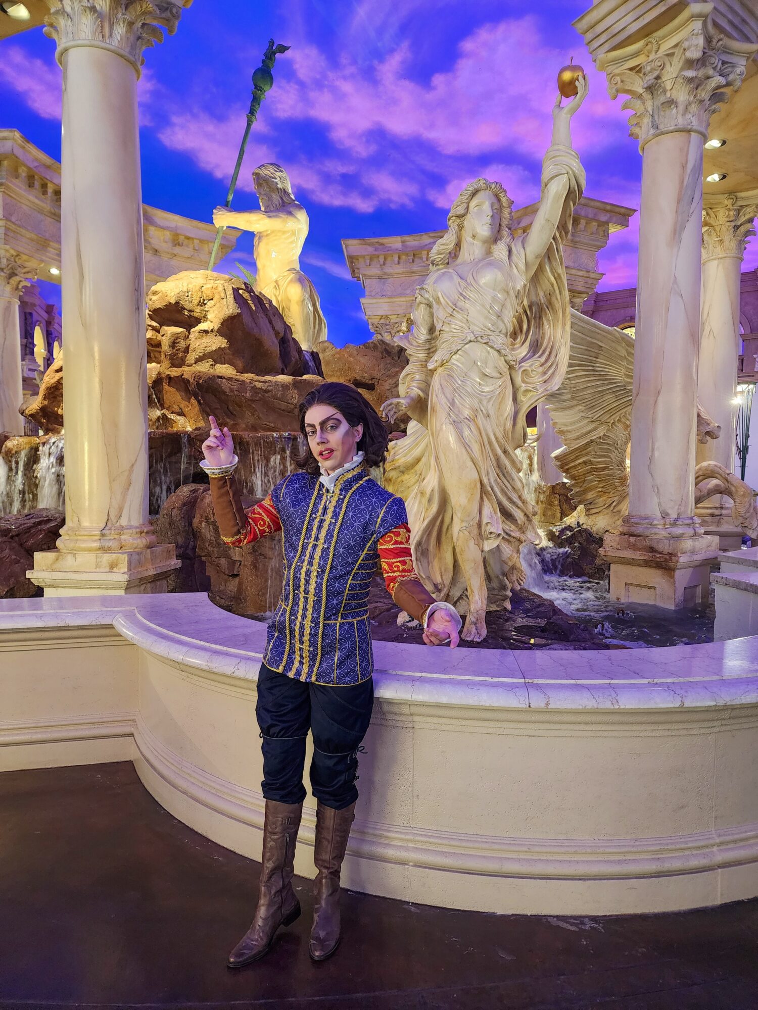 Person standing in front of a classical sculpture display with columns and a purple sky background.