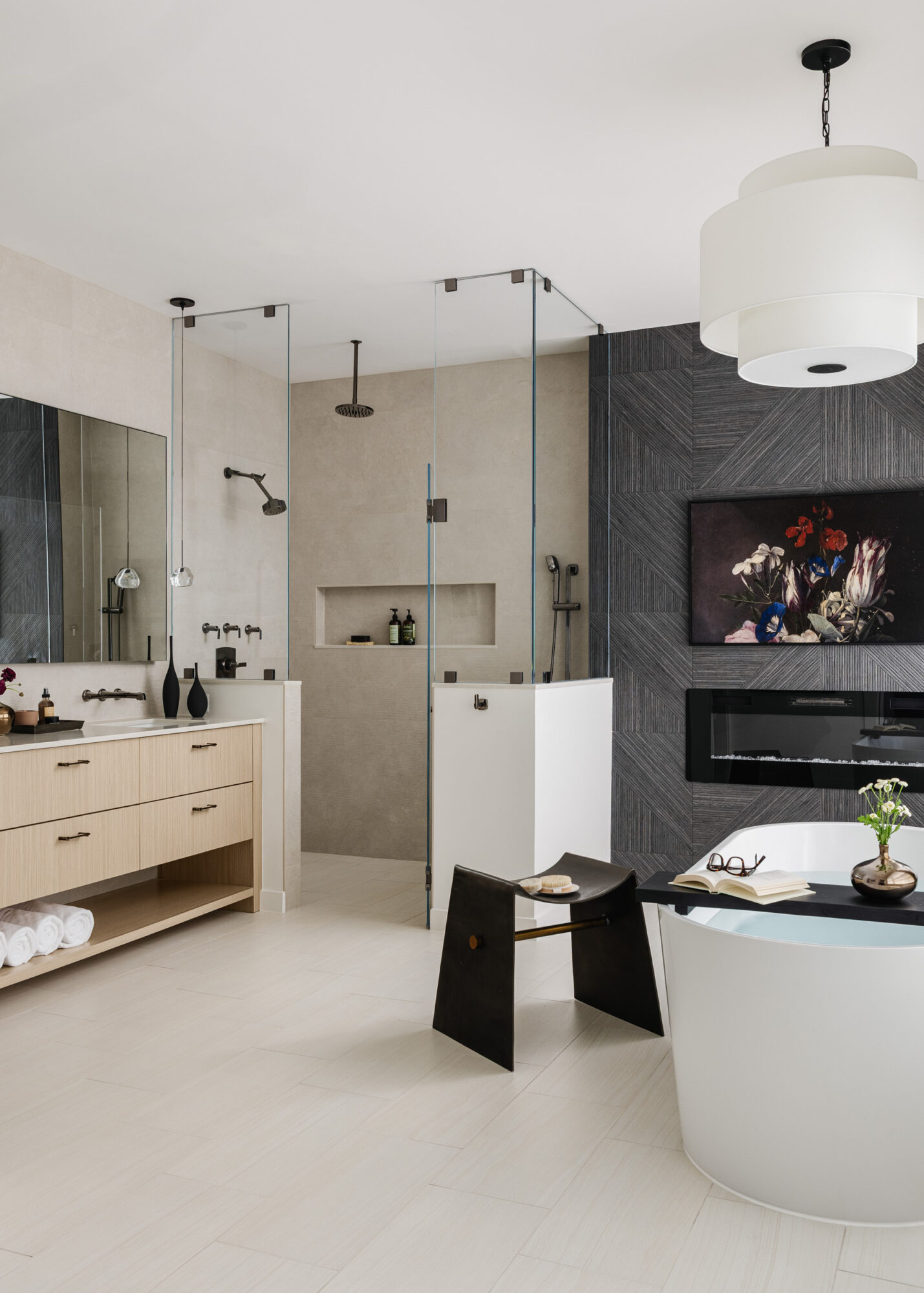 Modern bathroom with a bathtub, black wall, and a large mirror, featuring a black stool and a hanging light fixture.