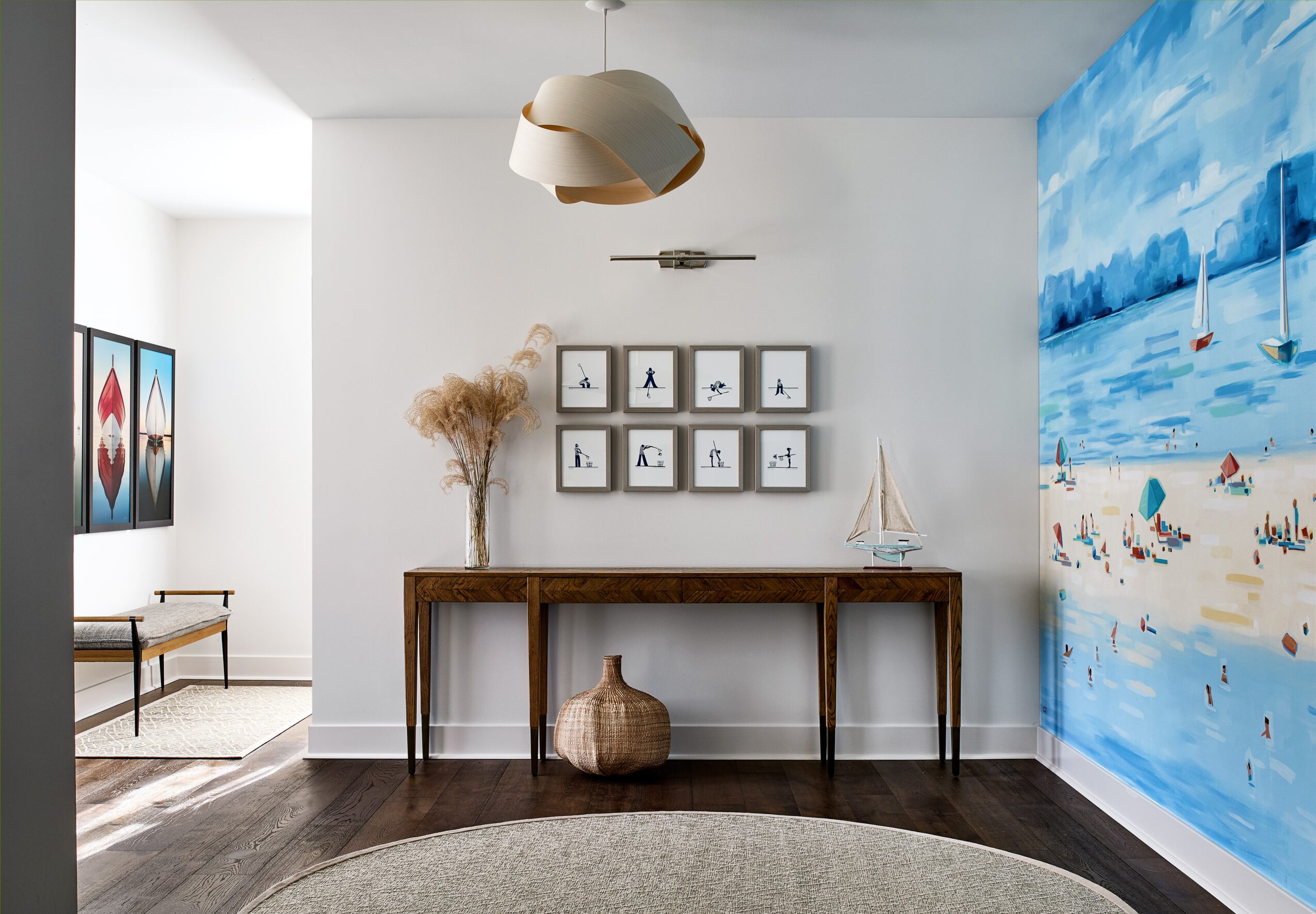 Interior with a wooden table, wall art, a large vase, and a beach mural on the right wall.