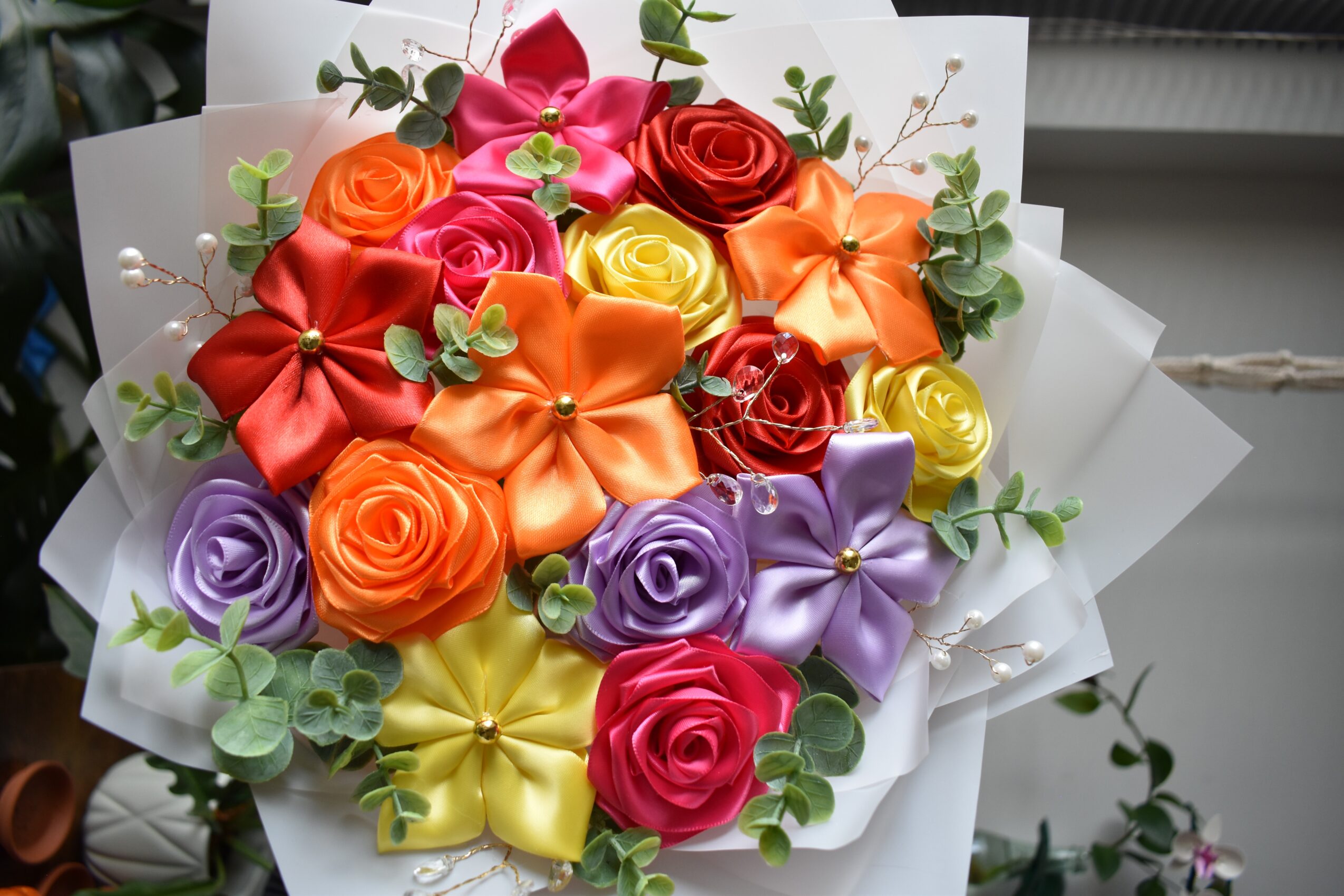 Bouquet of colorful roses, lilies, and greenery wrapped in white paper, arranged in a vibrant display.