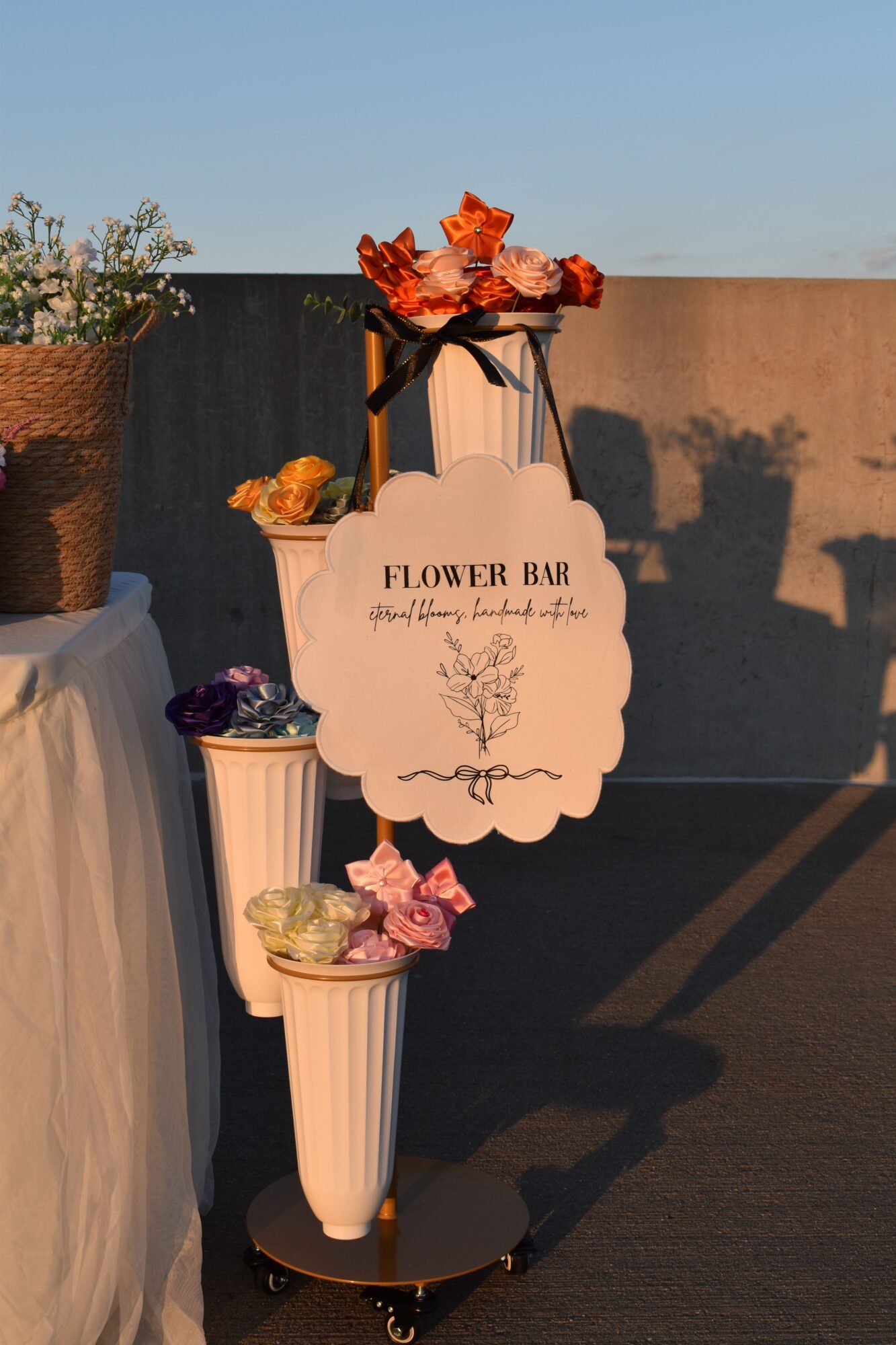 Decorative flower arrangement with a sign reading 'Flower Box' on a white column, with a dark background and shadow, and a tablecloth in the foreground.
