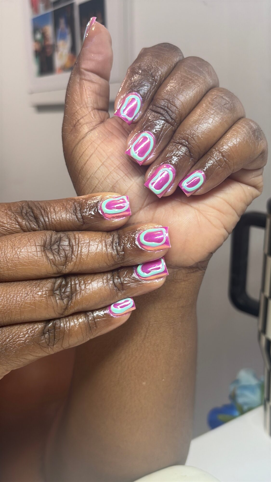 Two hands with colorful, striped nail art, one with darker skin and one with lighter skin, touching each other.