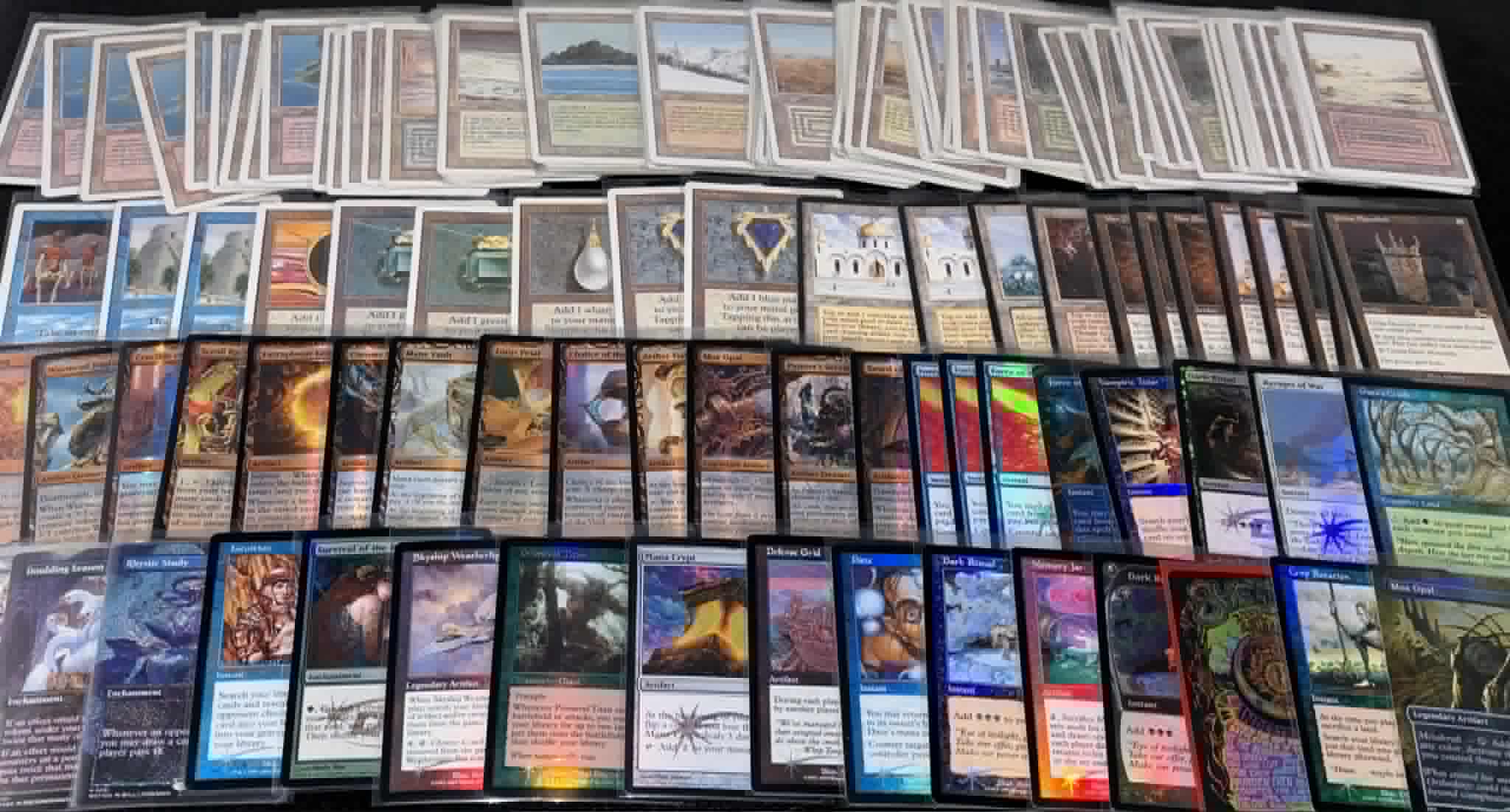Collection of trading cards arranged in rows, featuring various artwork and text, with some cards overlapping each other.