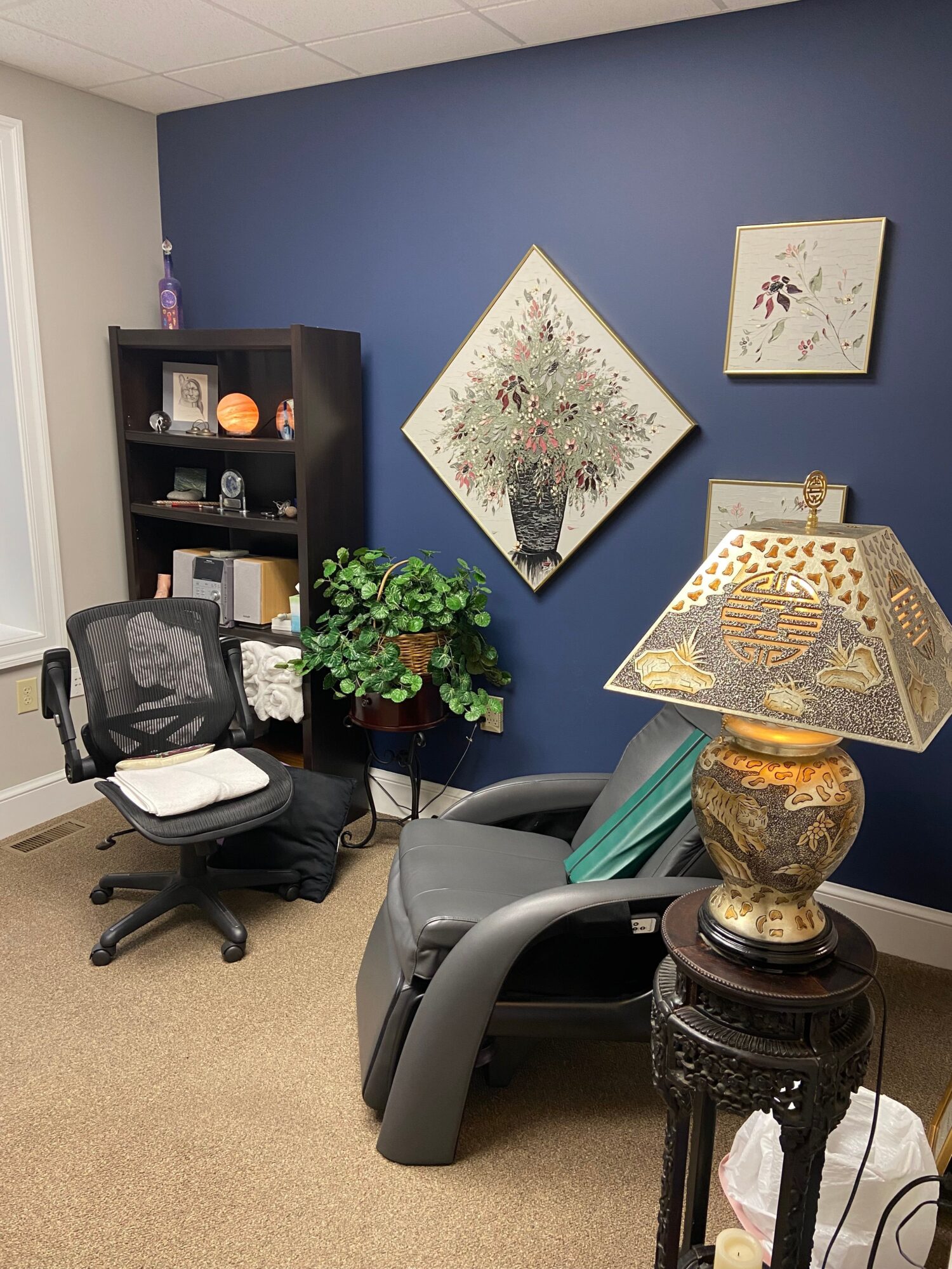 Decorative objects on a table, including a gold-colored lantern, a black telephone, and a potted plant, with wall art in the background.