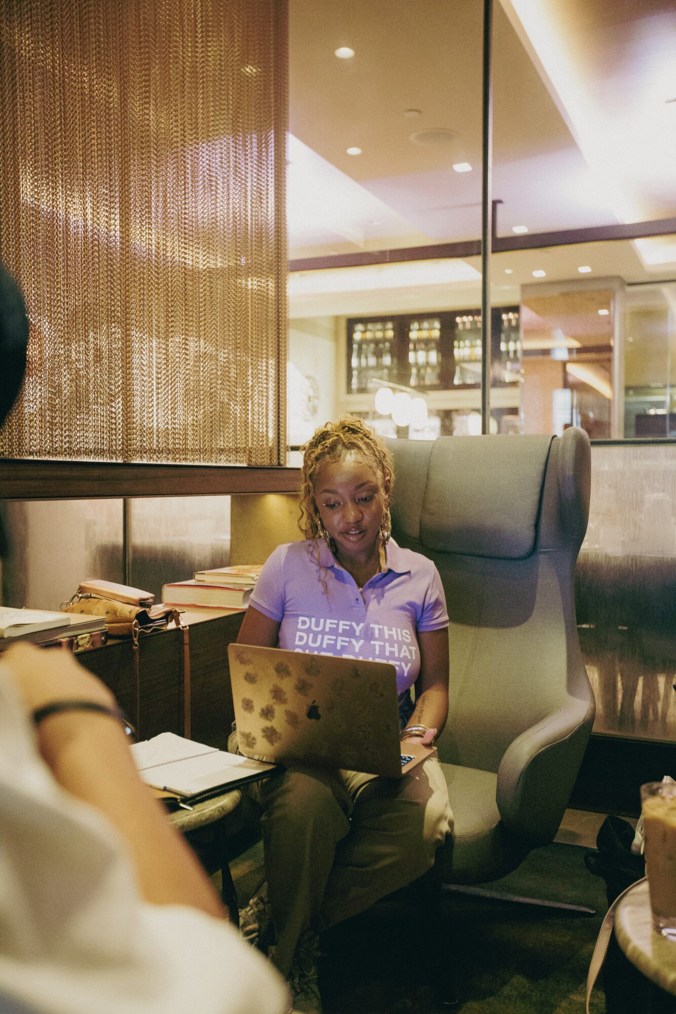 Woman sitting in a high-backed chair using a laptop in a modern indoor setting.