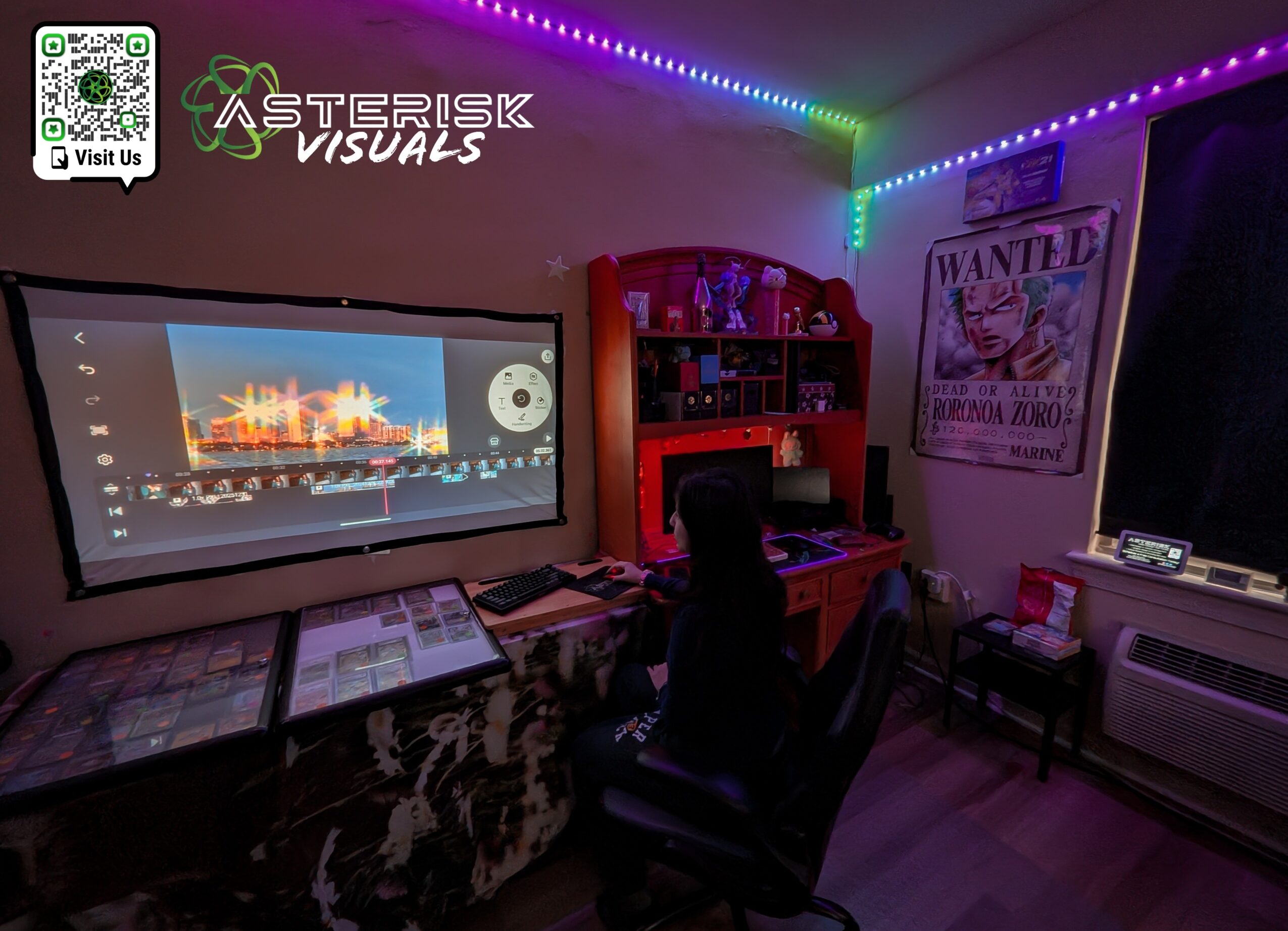 Room with computer desk, large monitor, colorful LED lights, and a poster on the wall.