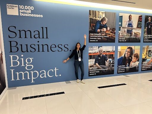 Person standing next to a wall with text and images about small businesses and their impact.