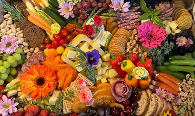 Colorful assortment of fruits, vegetables, flowers, and baked goods arranged together.