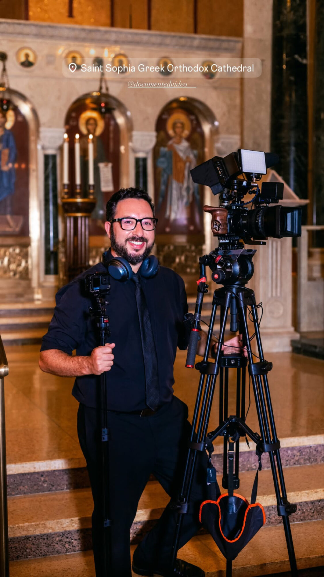 Man with camera equipment inside a church with religious icons in the background.