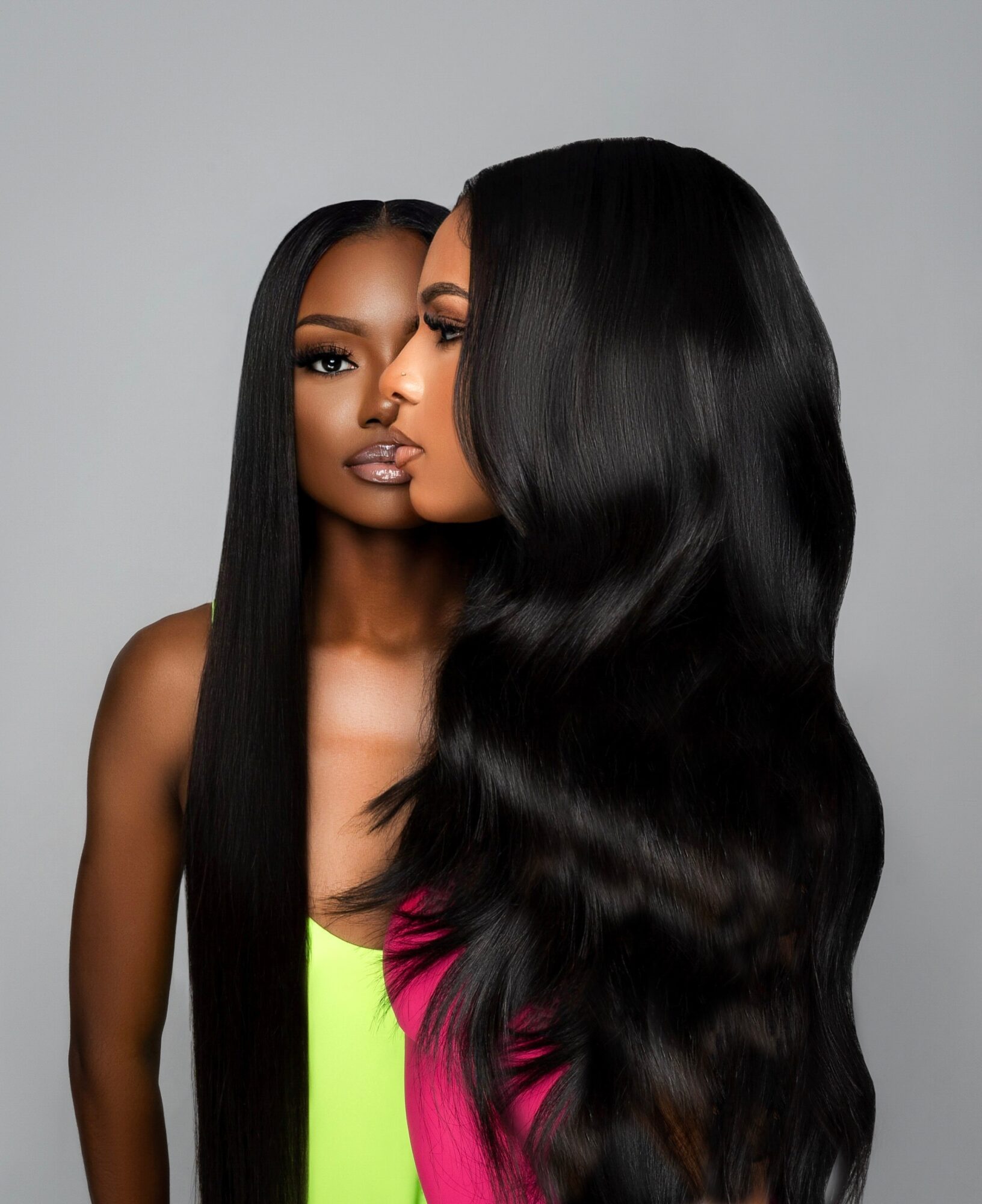 Two women with long, straight black hair, one facing forward and the other in profile, against a gray background.