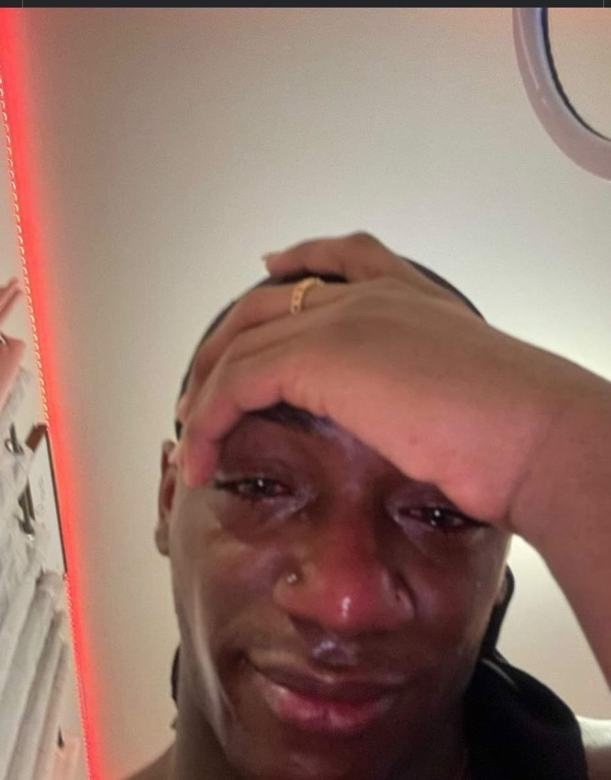Person with hand on forehead, tears and emotional expression, in an indoor setting.