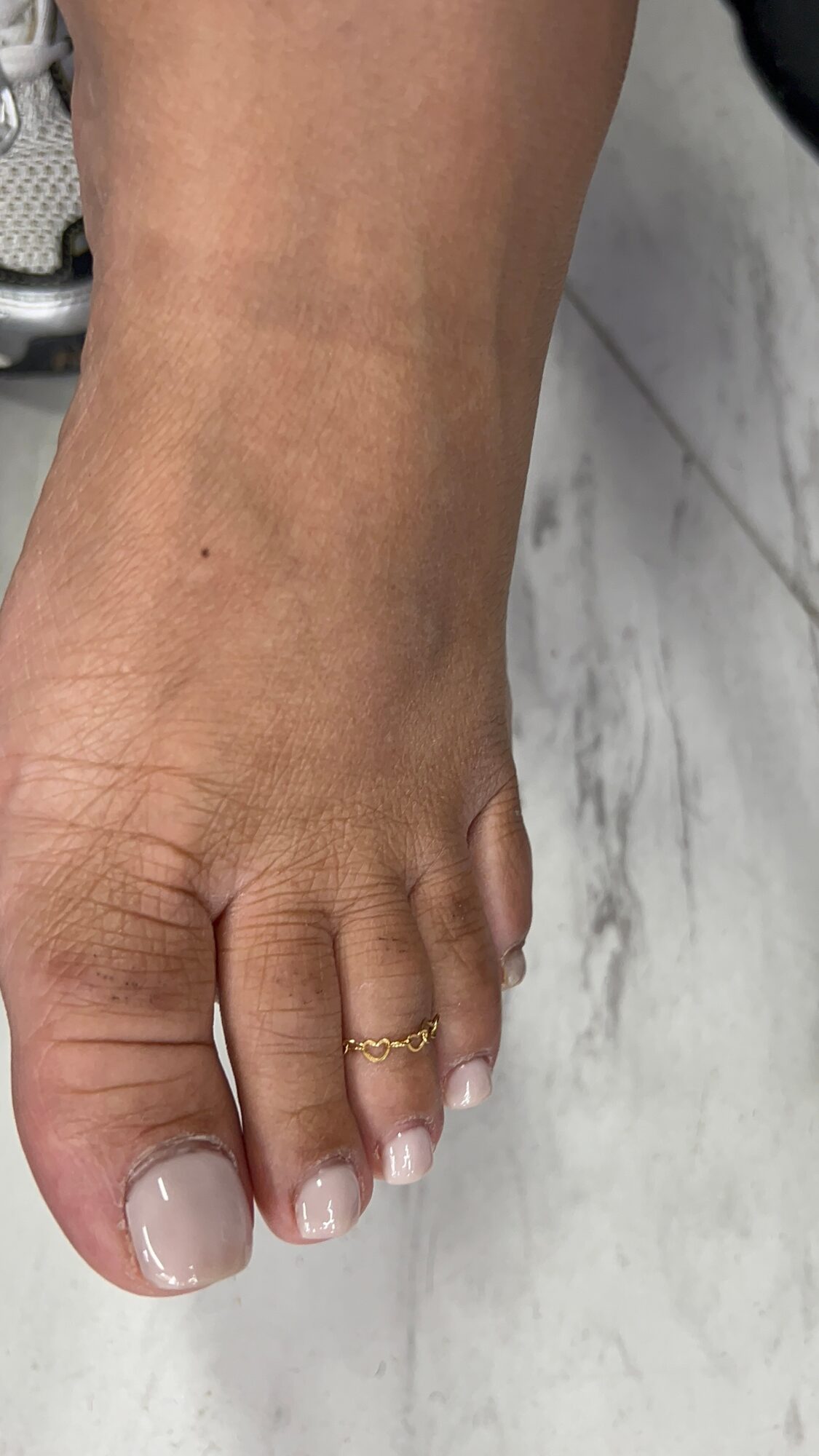 Close-up of a person's foot with toenails on a marble surface.