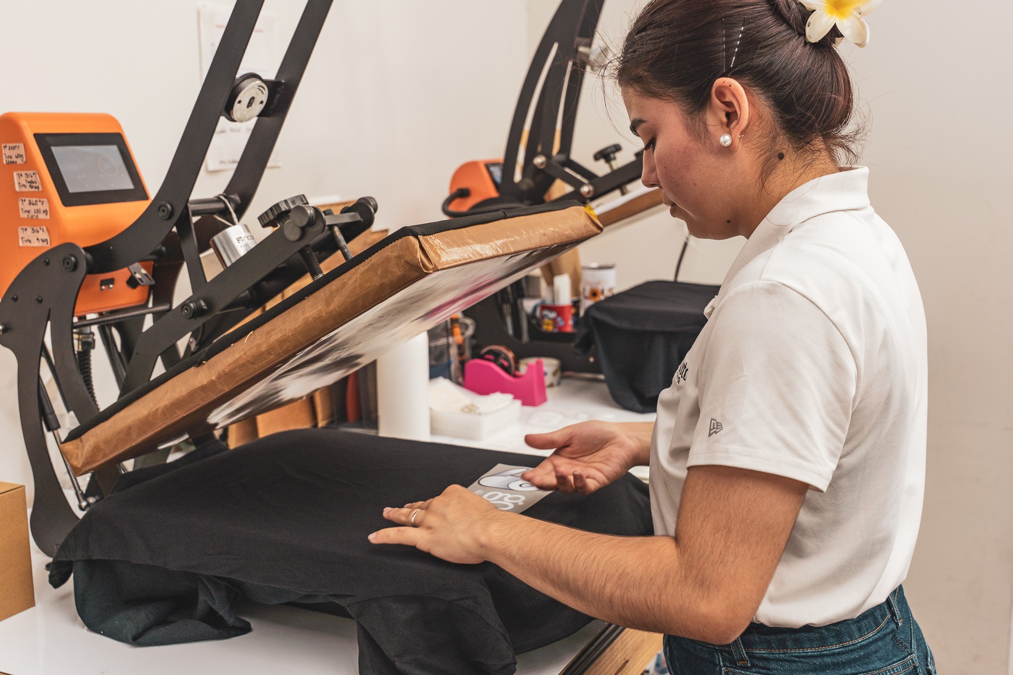 Woman in white shirt working with fabric on a sewing machine in a workshop.