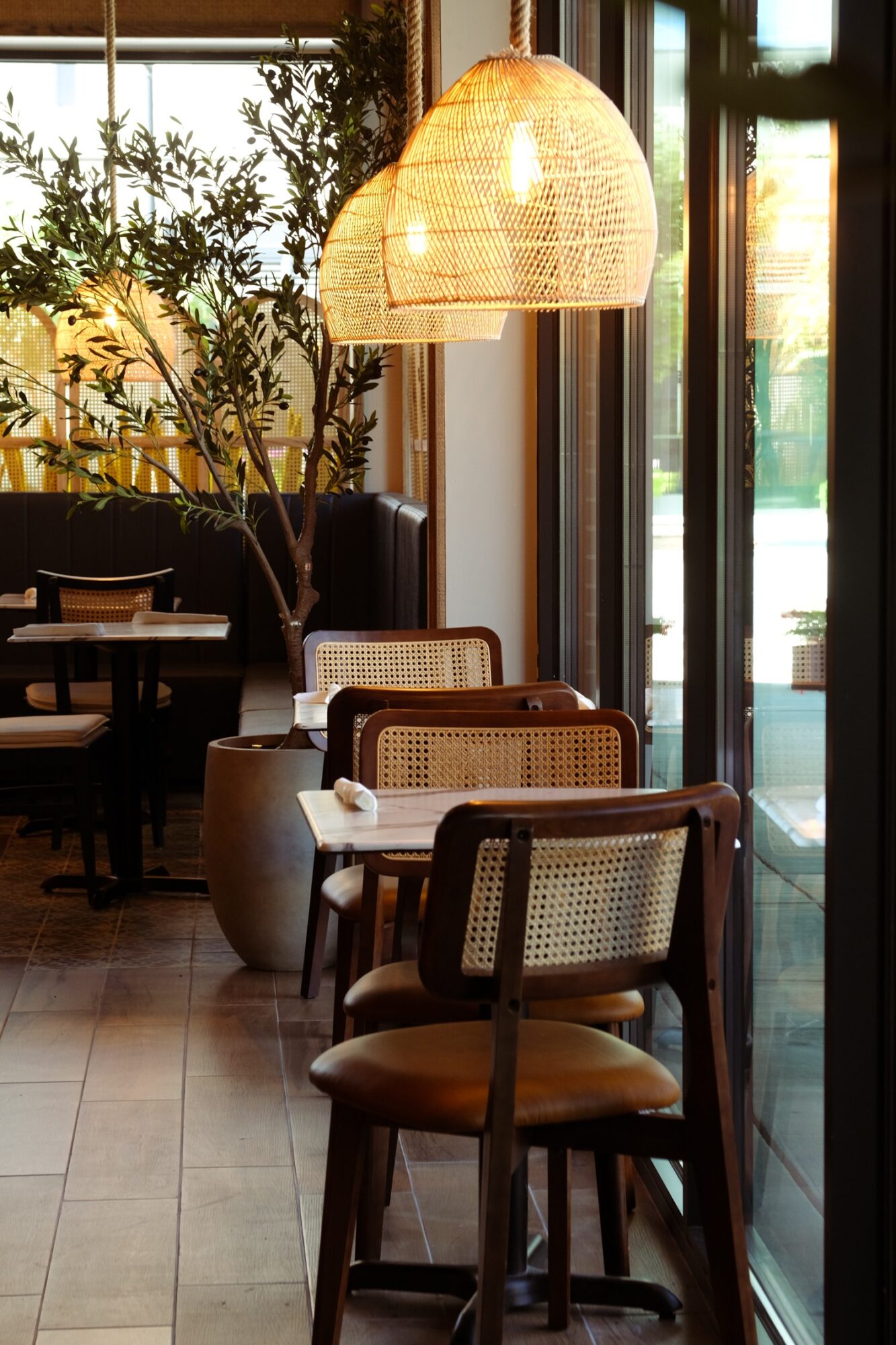 Interior of a cafe with chairs, a hanging lamp, and large windows letting in natural light.