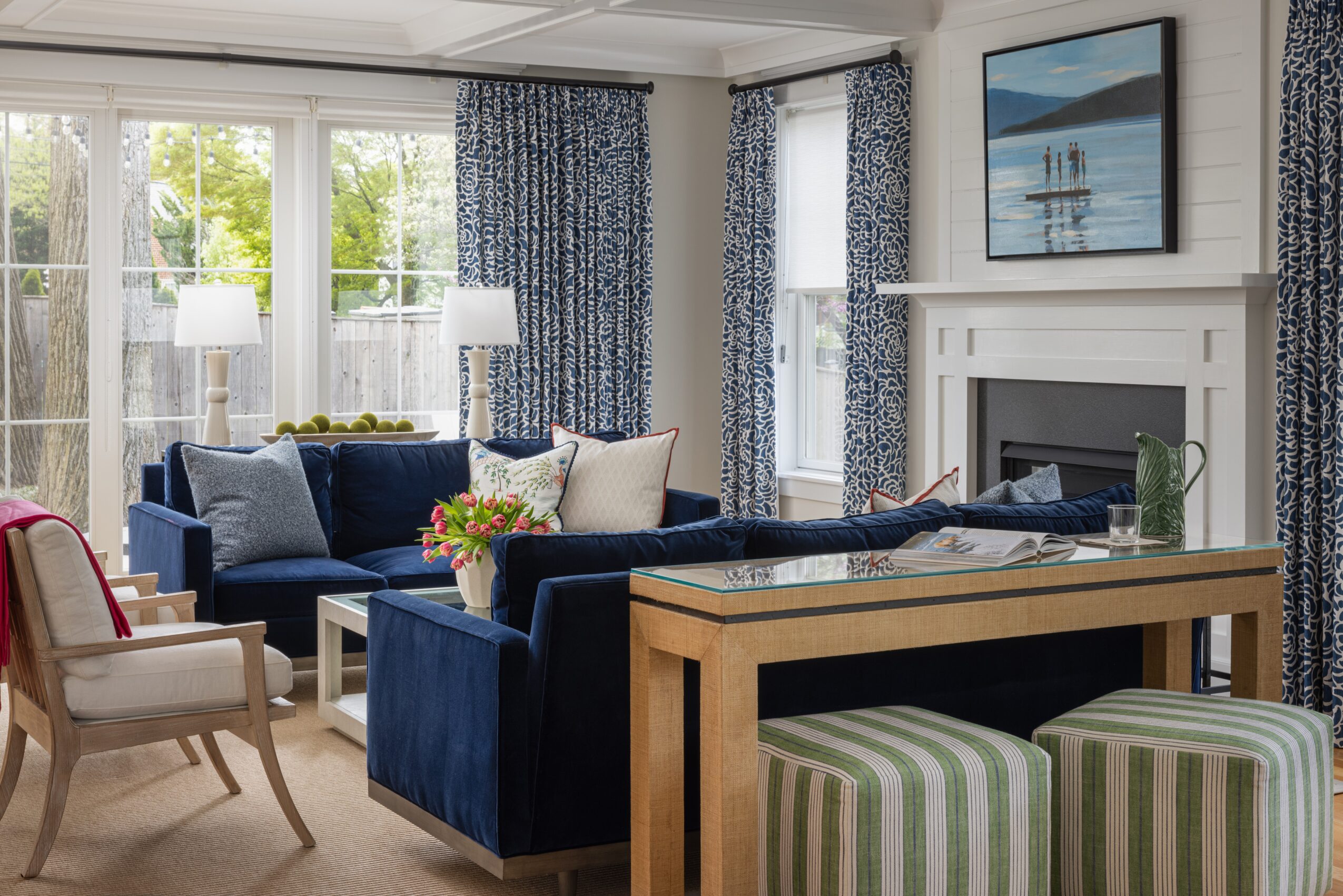 Living room with blue sofas, striped curtains, a fireplace, and a wall-mounted TV, with large windows and a view outside.