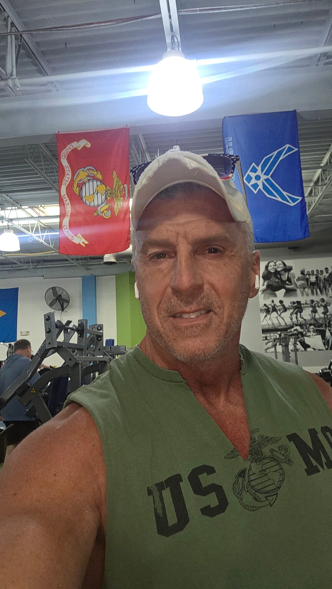 Man taking a selfie in a gym with flags hanging from the ceiling behind him.