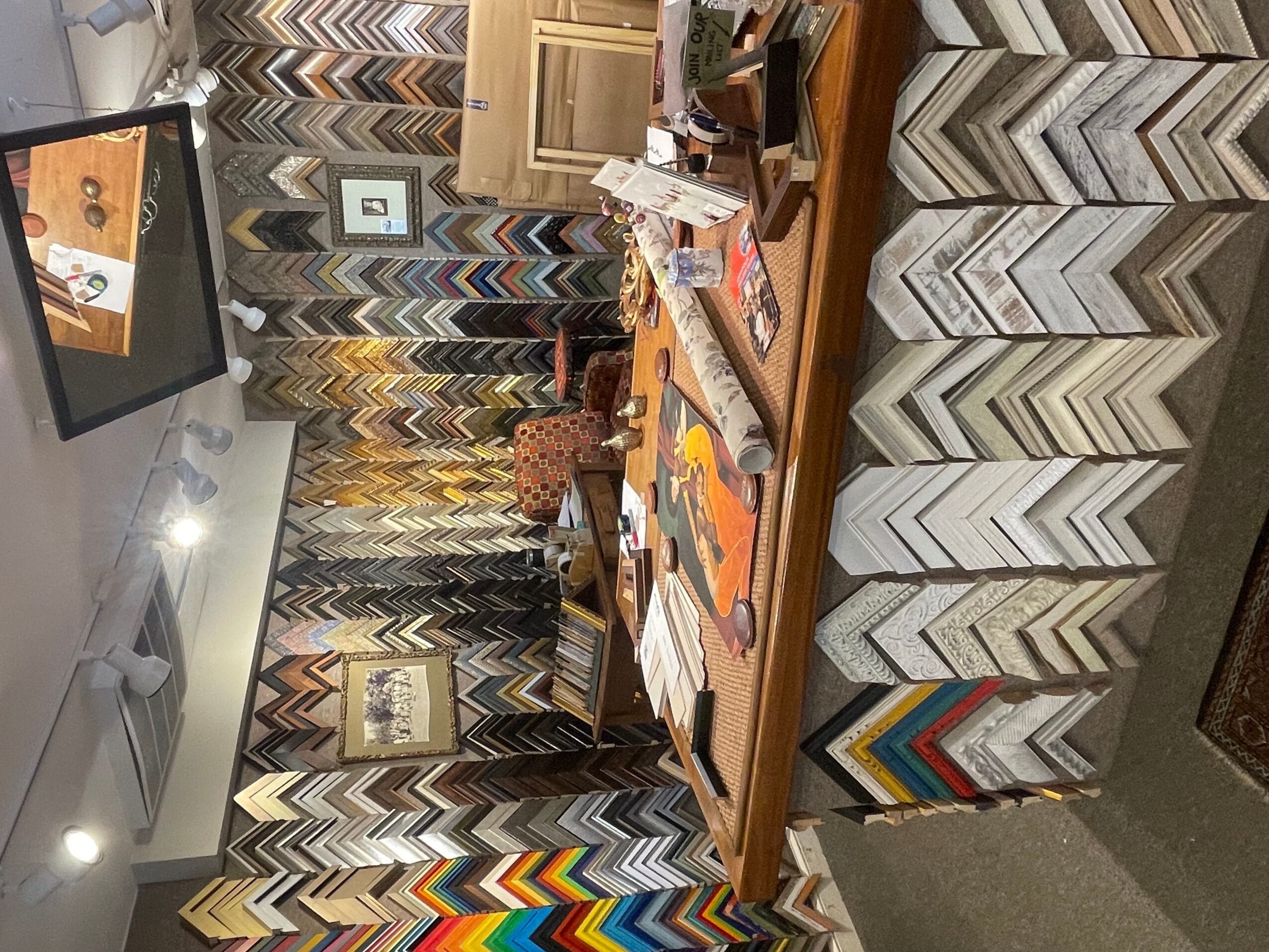 Room with a wooden table, patterned curtains, and a TV mounted on the wall, cluttered with papers and books.