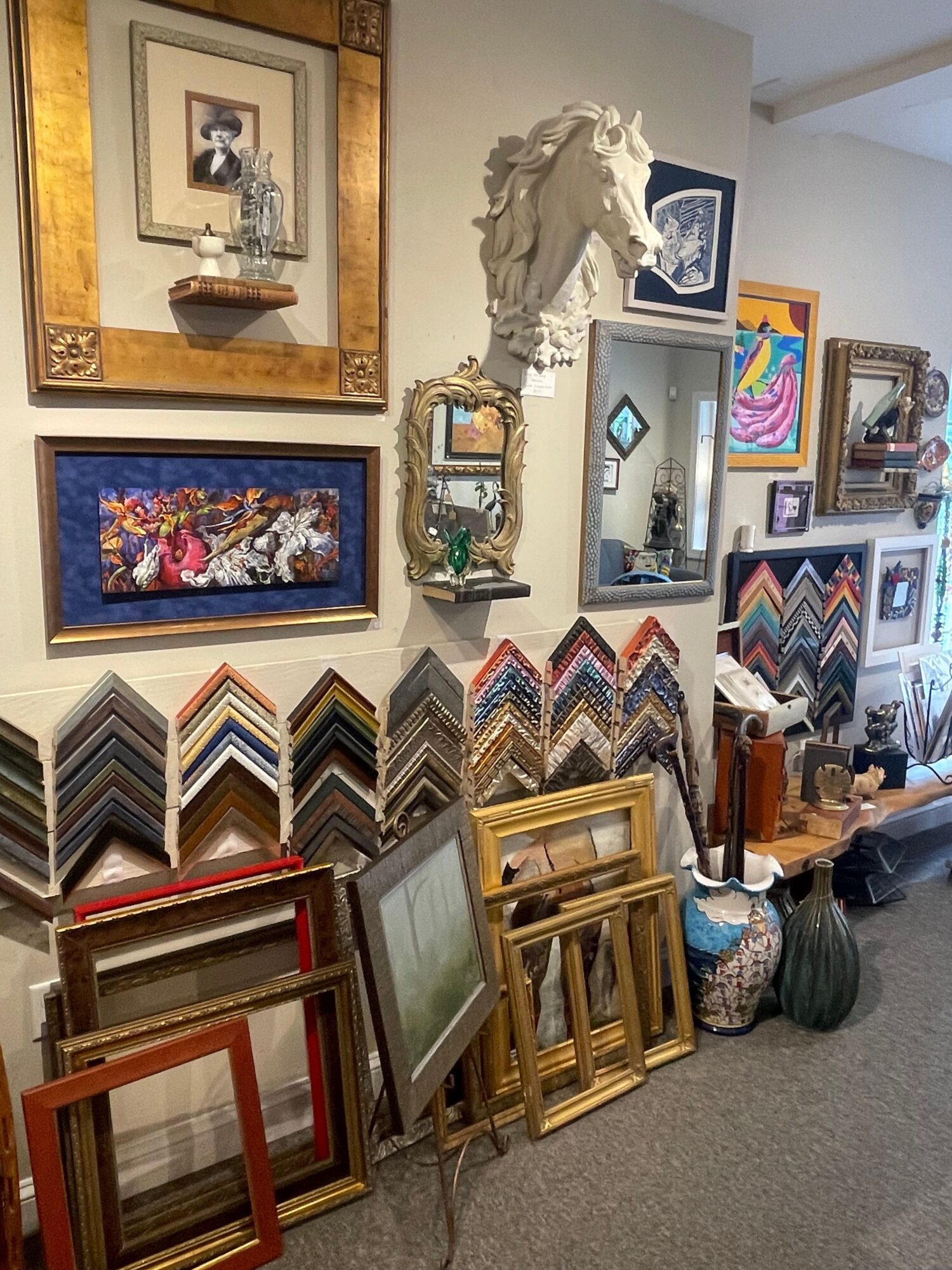 Room with various framed artwork, furniture, and decorative items arranged on the wall and floor.