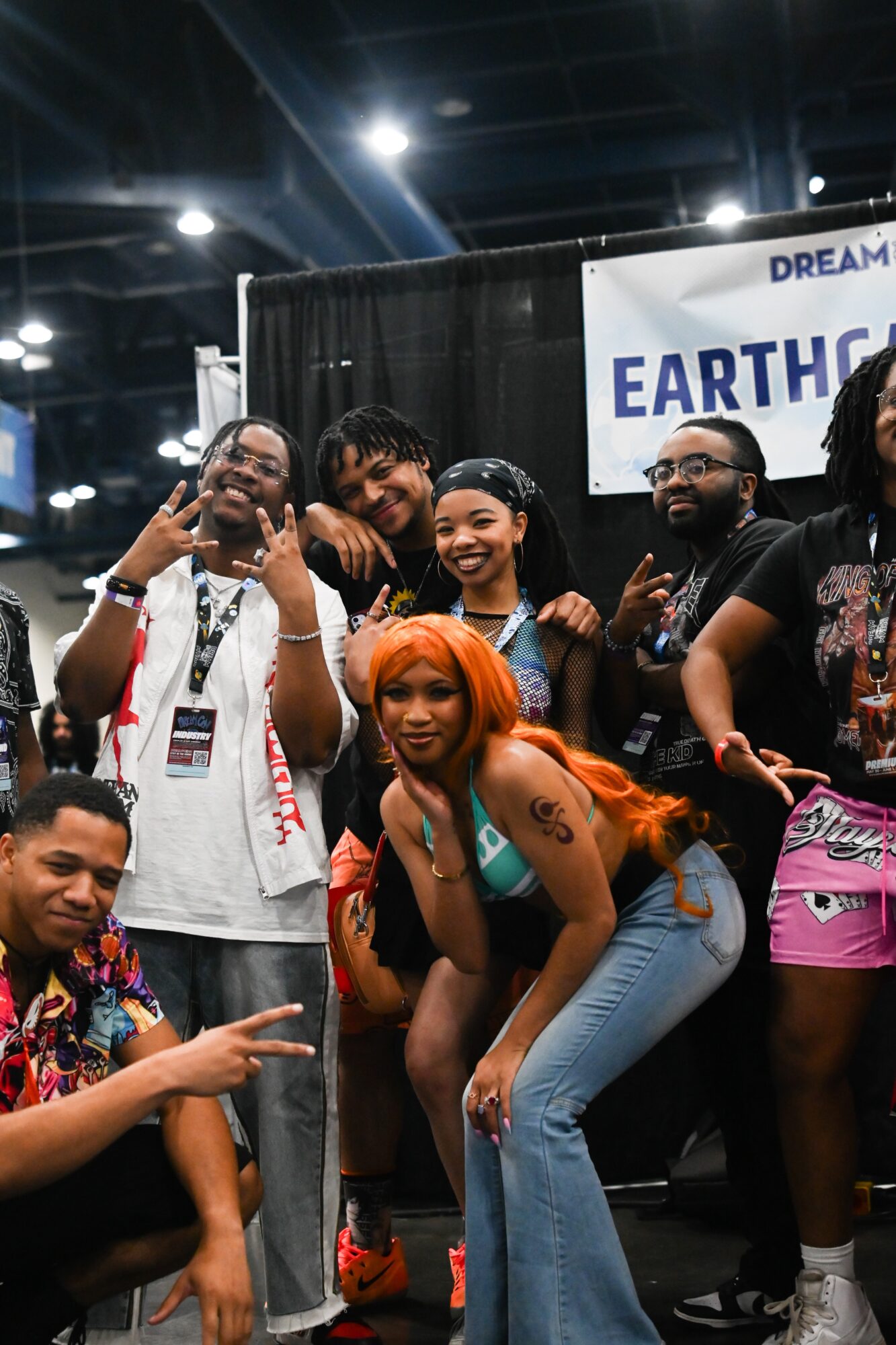 Group of people smiling and posing at an event, with a banner reading 'EARTH' in the background.