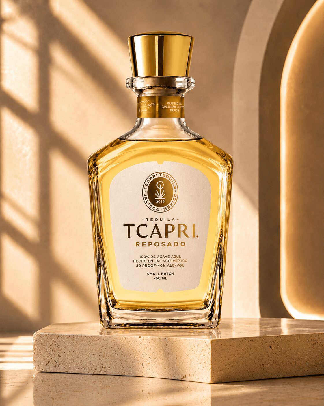 A bottle of Tcapri Reposado tequila on a beige surface with sunlight and shadows, gold cap, and white label.