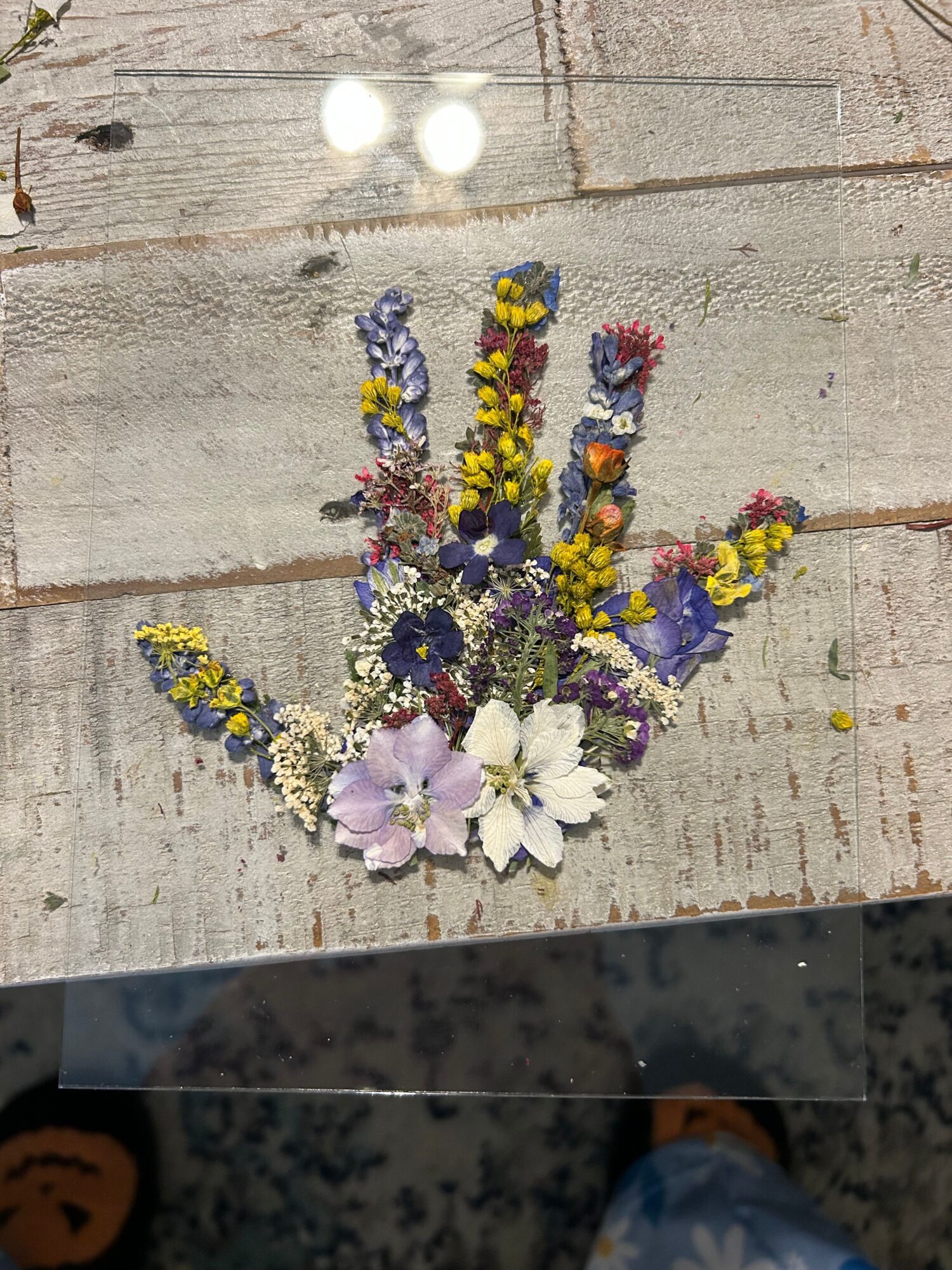 Flower arrangement with white lilies, purple, yellow, and blue flowers on a wooden surface.
