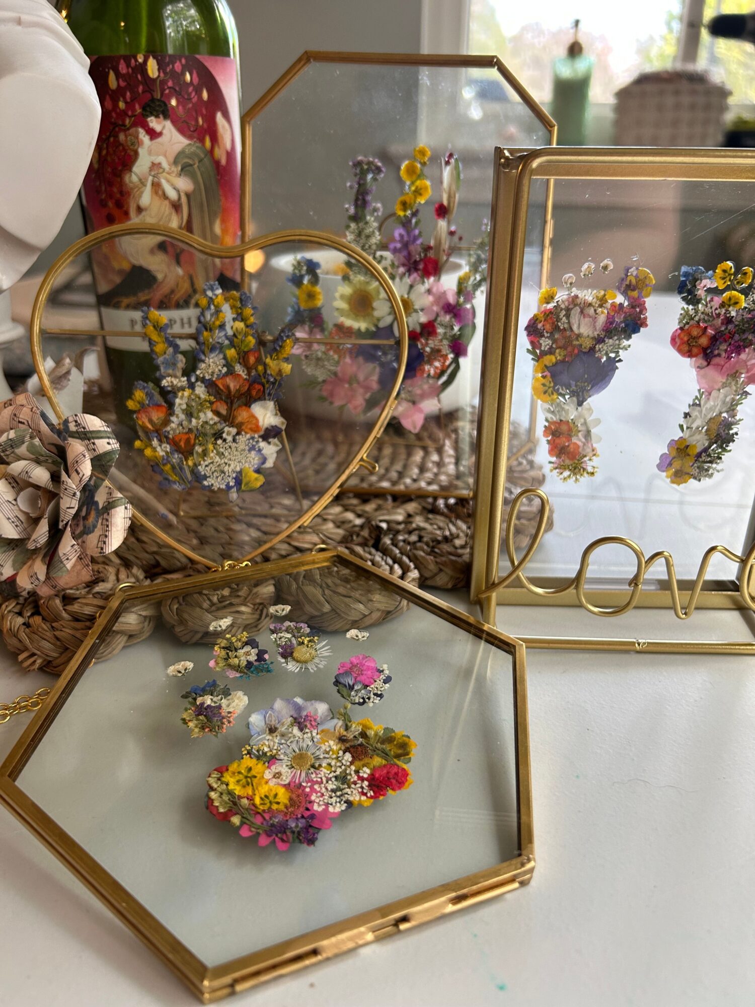 Display of various colorful flower arrangements in glass and metal containers on a white surface.