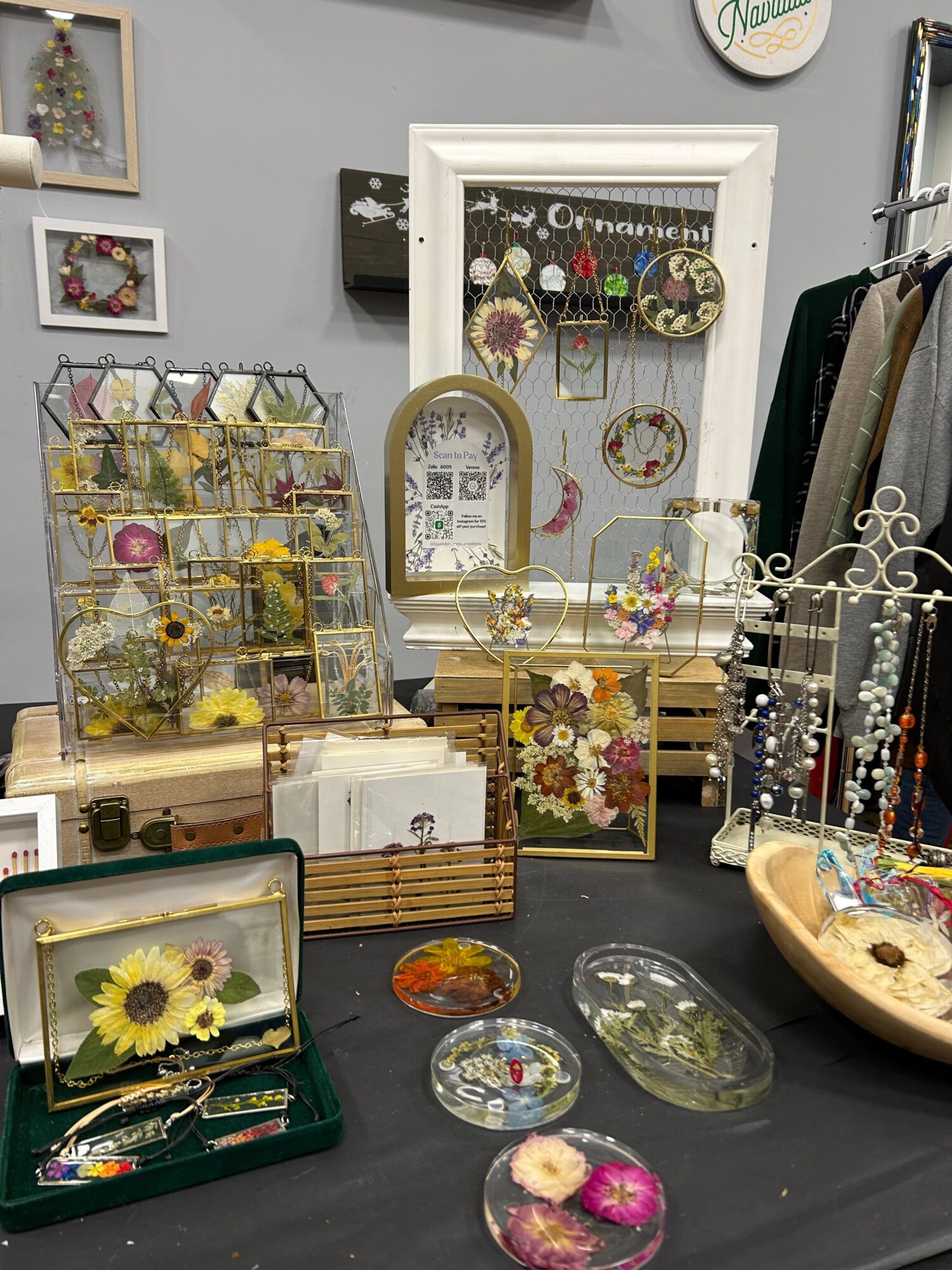 Display of jewelry, flowers, and decorative items on a table with framed artwork in the background.