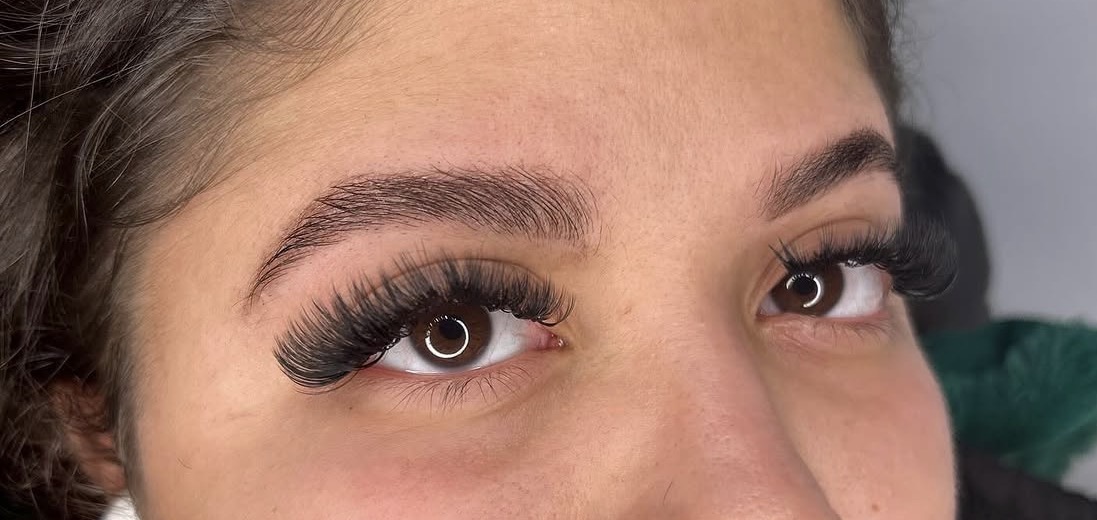Close-up of a person's eyes with long, thick eyelashes and well-groomed eyebrows.
