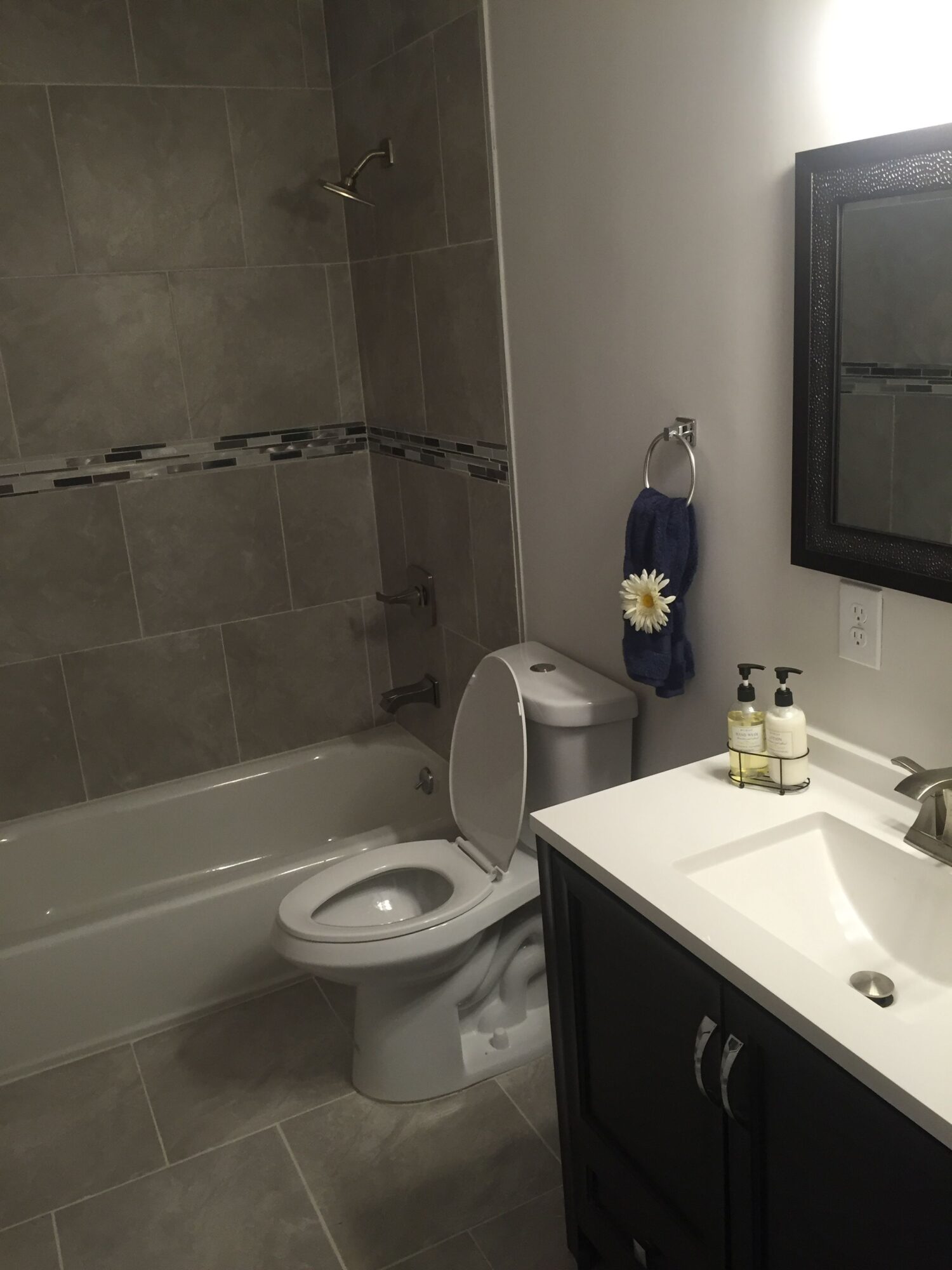 Bathroom with sink, mirror, toilet, and bathtub, viewed from the side, with a towel hanging on the wall.