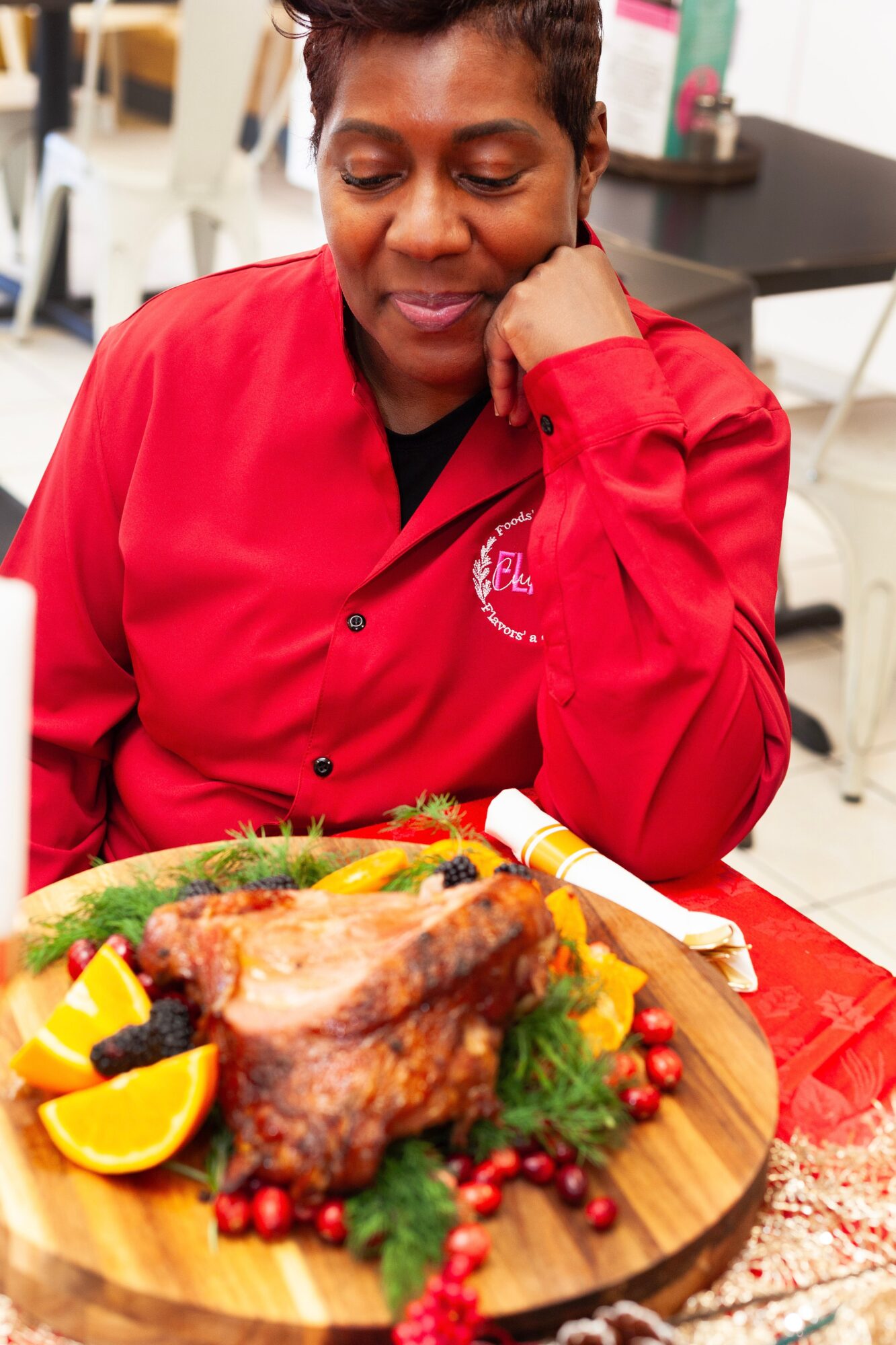 Person in red shirt looking at a large cooked meat dish with lemon slices and garnishes on a wooden board.