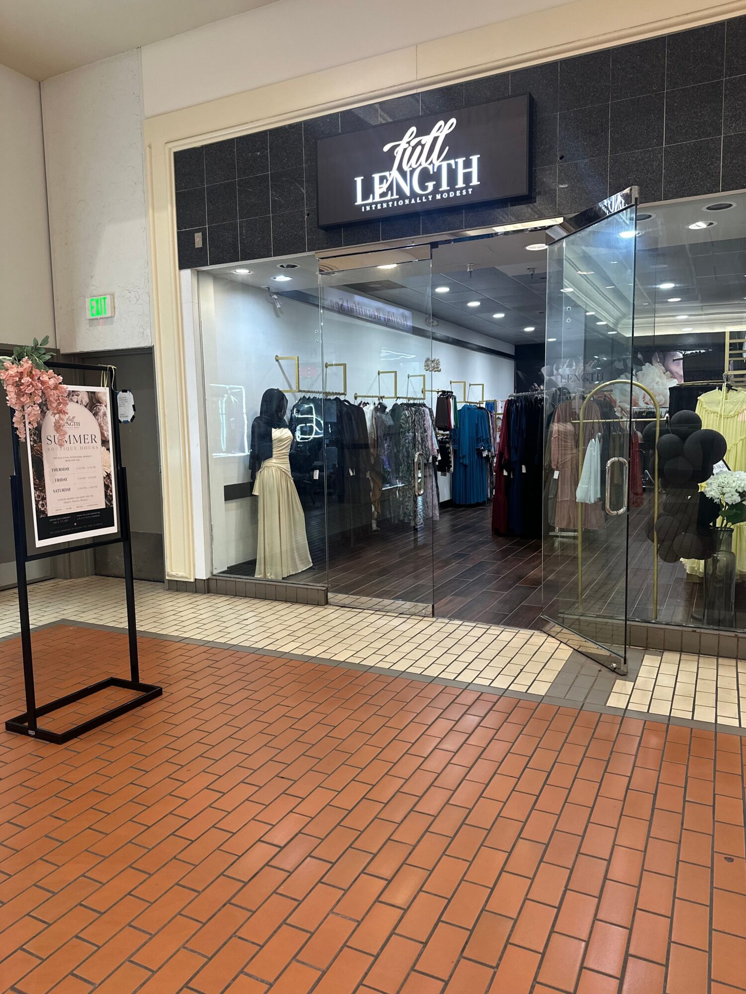 Store entrance with glass doors, clothing displays, and a sign reading 'LENGTH' above the entrance.