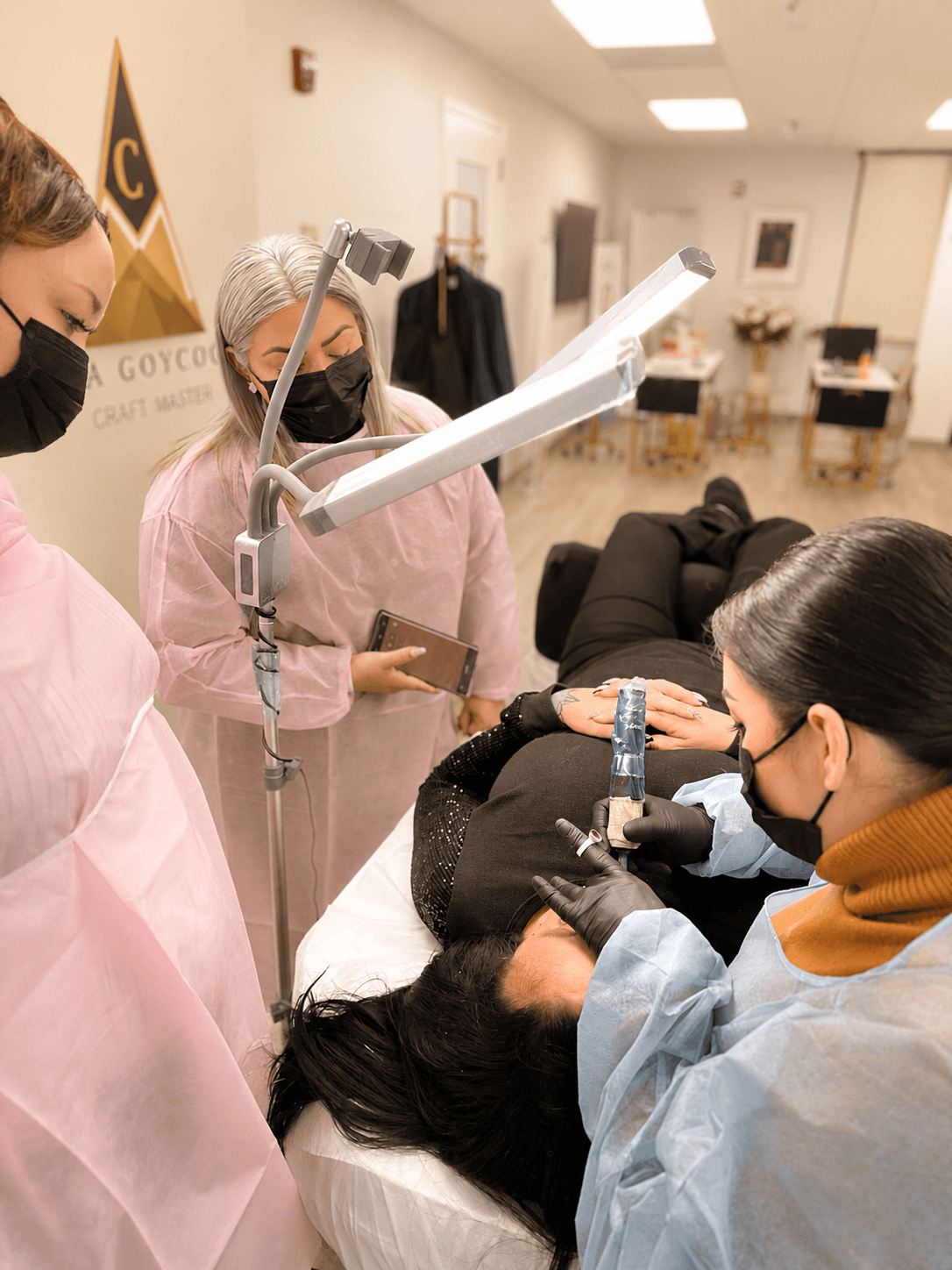 Dental professionals and a patient in a clinical setting, with one professional examining the patient's mouth, all wearing masks.