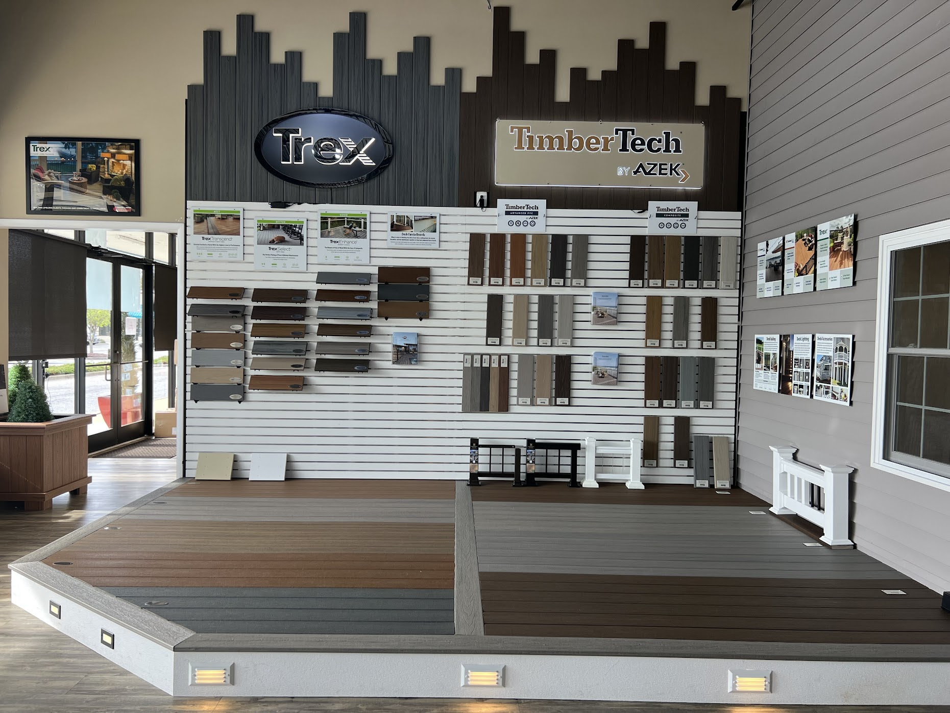 Display wall with wood samples and signage, in a showroom with a wooden floor and a window on the left.