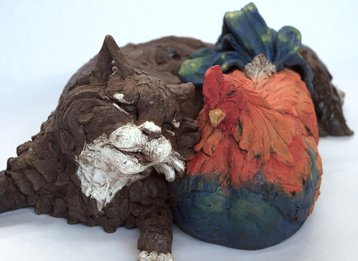 Clay sculpture of a sleeping cat next to a large, colorful pumpkin with green leaves, on a white background.