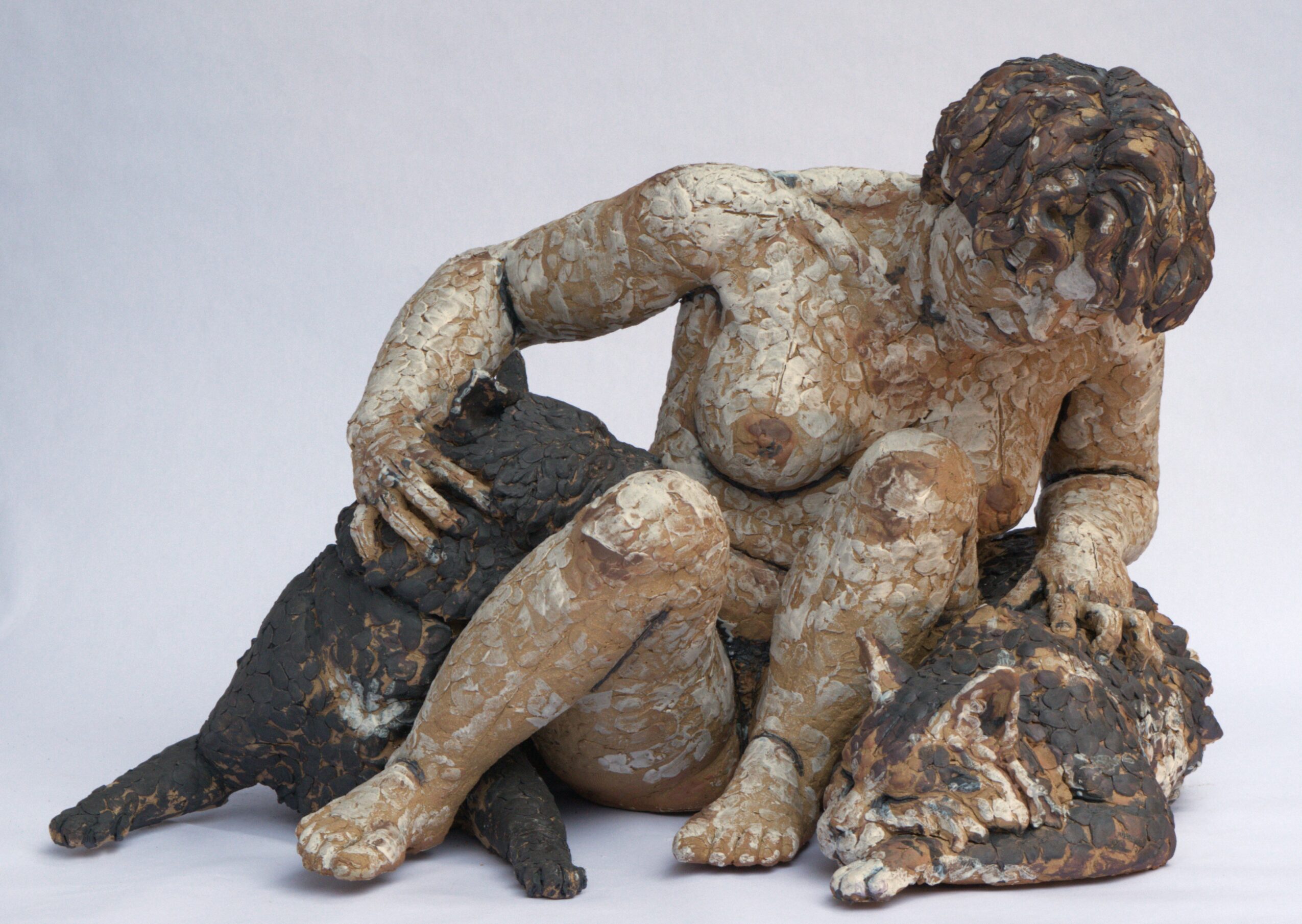 Sculpture of a woman with curly hair, sitting with a dog and a turtle, holding the dog with one hand.