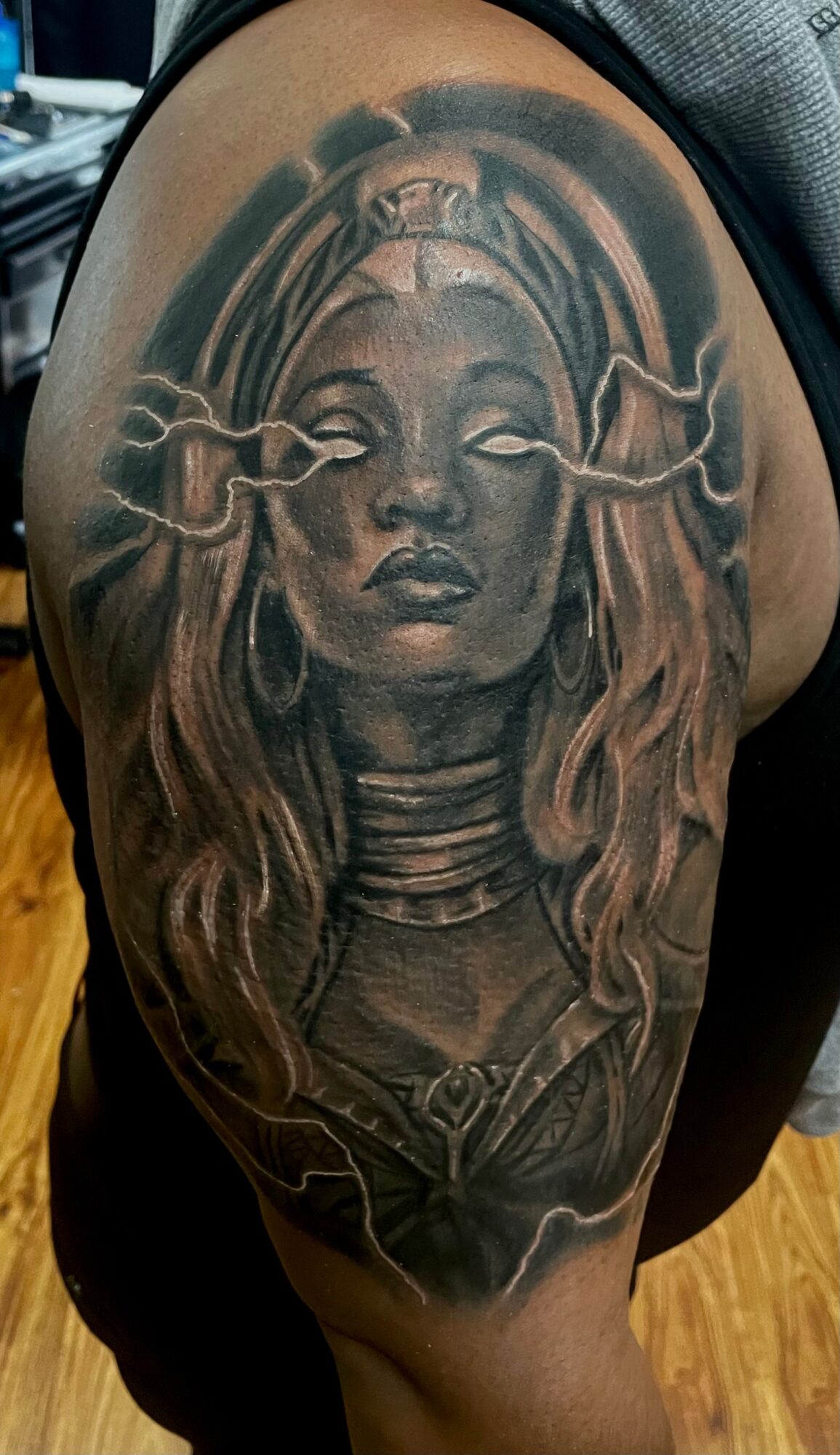 Tattoo of a woman with long hair, closed eyes, and smoke-like elements around her head, on a person's thigh.