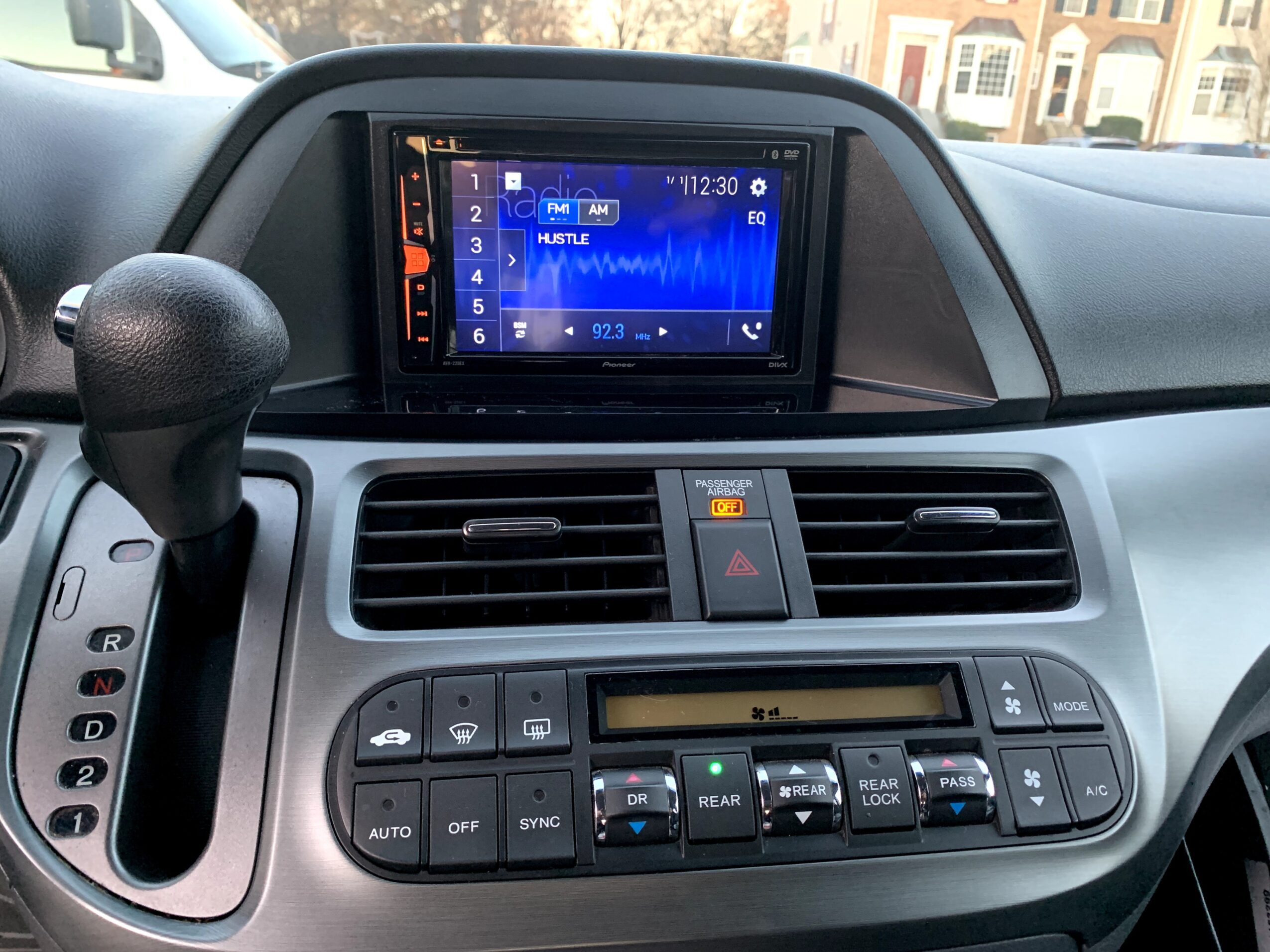 Car dashboard with touchscreen display, air vents, and climate control buttons, viewed from the driver's seat.