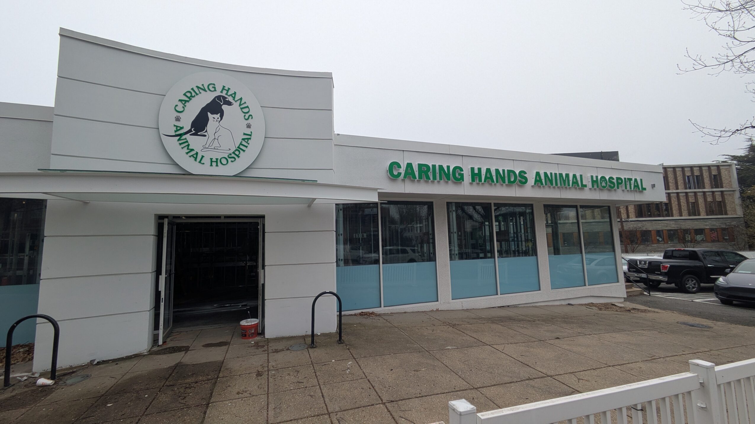 Caring Hands Animal Hospital building with a sign and large windows, parking lot in front, overcast sky.