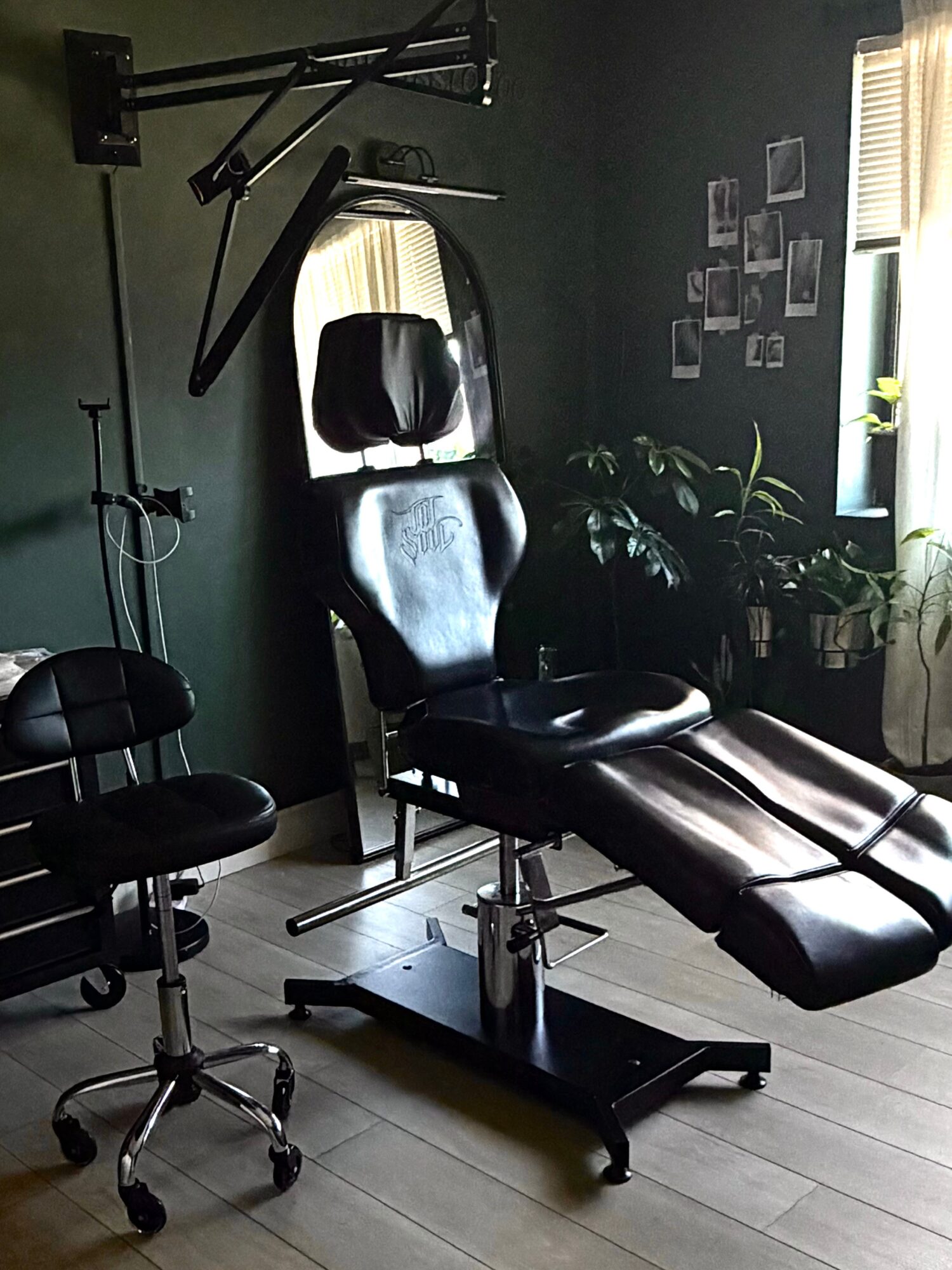 Medical examination or massage table in a room with dark green walls, window with blinds, and framed photos.