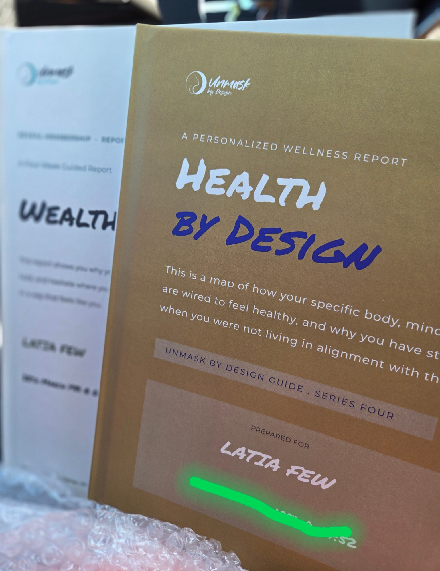 Two wellness report brochures, one gold and one white, with text about health and design, placed on a surface.