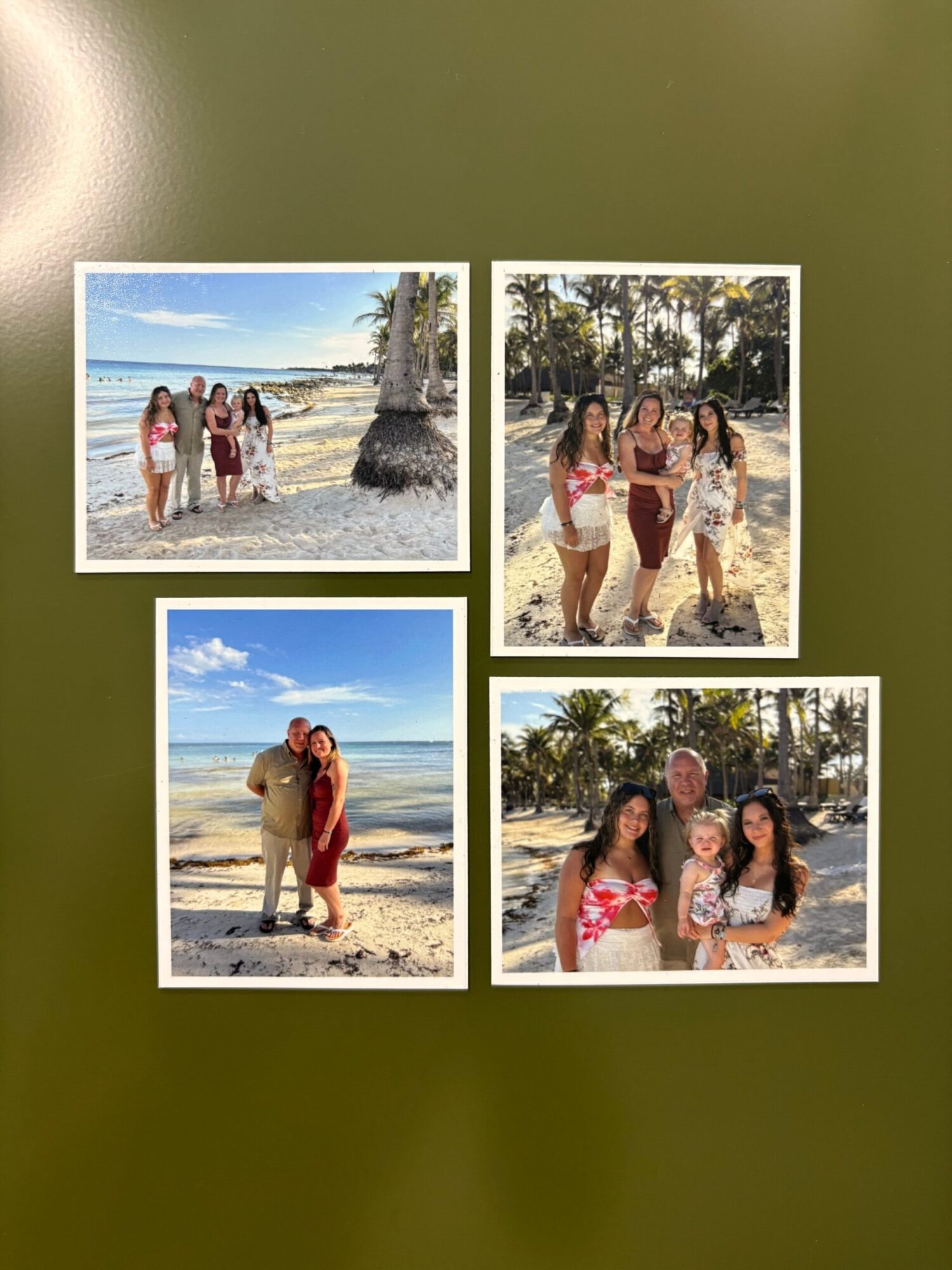 Four people on a beach, some standing in water, others walking on sand, with trees and sky in the background.