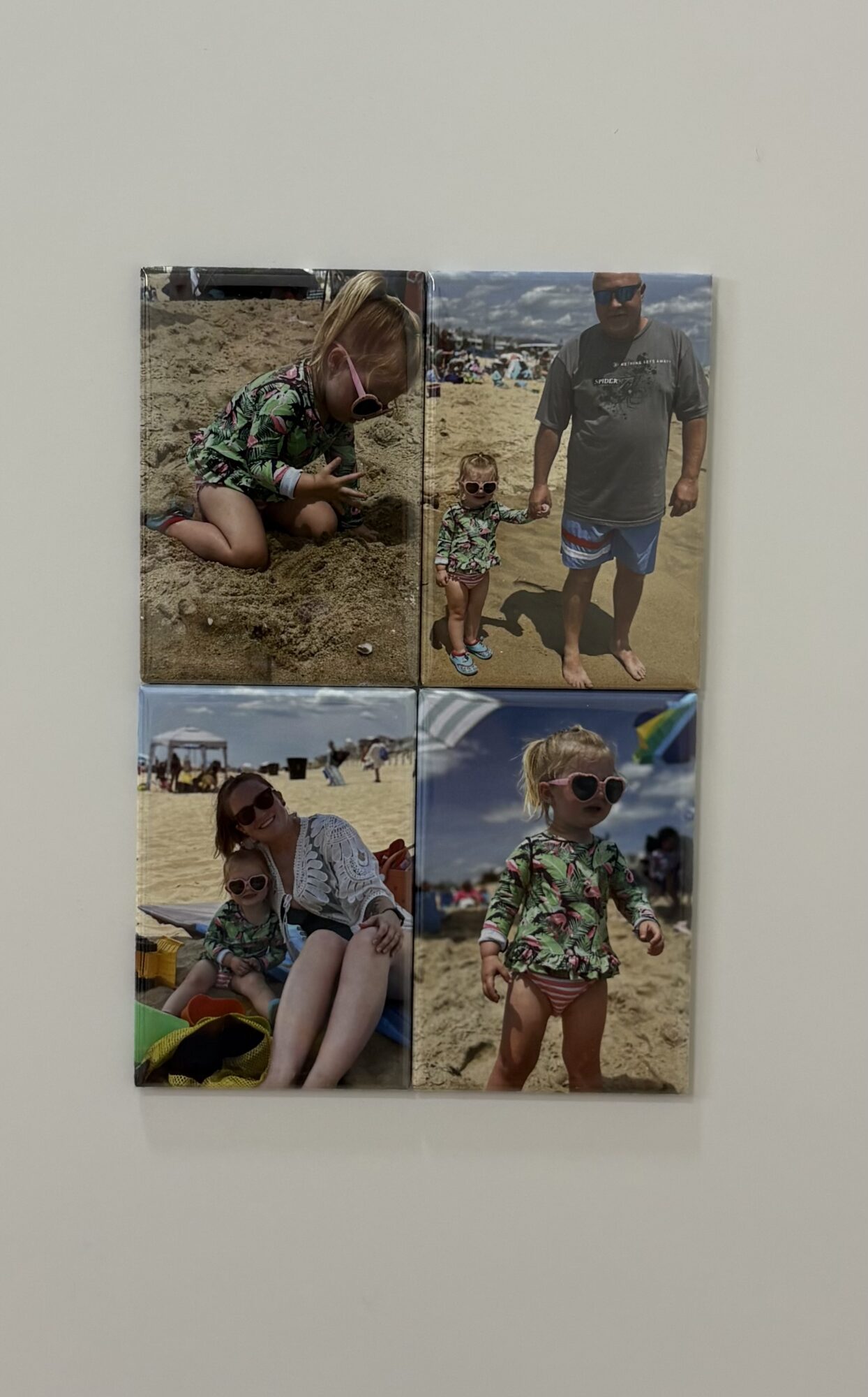 Four children at the beach, some wearing sunglasses, playing in sand and water, with a clear sky and beach background.